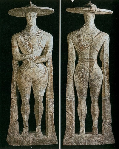 Il guerriero di Capestrano (Chieti) Il Guerriero di Capestrano è una scultura in pietra e marmo risalente al VI secolo a.C., testimonianza dell'arte italica, rinvenuta in una necropoli presso l'antica città di Aufinum, vicino a Capestrano in provincia dell'Aquila. La statua raffigura un guerriero appartenente al popolo italico dei Piceni ed è considerata una delle opere più imponenti e affascinanti della scultura pre-romana. Oggi è custodita presso il Museo Archeologico Nazionale d'Abruzzo a Chieti, dove rappresenta un'importante icona del patrimonio storico e artistico della regione. La scoperta avvenne nel 1934, quando Michele Castagna, durante lavori agricoli nella località di Cinericcio, si imbatté casualmente nella statua con le gambe spezzate. Gli scavi successivi, diretti dall'archeologo Giuseppe Moretti, portarono alla luce una necropoli con tombe e corredi funerari databili tra il VII e il IV secolo a.C. I frammenti della scultura, tra cui il caratteristico copricapo, furono recuperati e utilizzati per la ricostruzione e il restauro, permettendo di restituire alla statua il suo aspetto originario. La figura maschile, alta 2,10 metri senza la base, si presenta in posizione eretta con le braccia ripiegate sul petto. Il guerriero è equipaggiato con un elmo da parata a disco che copre la testa, mentre una maschera cela il volto. Il torace è protetto da dischi metallici, fissati da corregge, e il ventre è difeso da una corazza in cuoio o metallo, sostenuta da un cinturone. Le gambe sono protette da schinieri e i piedi calzano sandali. Il guerriero porta una spada e un pugnale appesi al petto e impugna una piccola ascia. I dettagli ornamentali includono una collana rigida con pendaglio e bracciali sugli avambracci, mentre il copricapo, simile a un sombrero, è interpretato come elmo da parata o scudo trasportato sulla testa. L'iscrizione incisa su uno dei pilastrini laterali, in lingua sud picena, è oggetto di dibattito tra gli studiosi. Secondo una delle interpretazioni, il testo si tradurrebbe come: "Me, bella immagine, fece Aninis per il re Nevio Pompuledio" (Adriano La Regina), mentre un'ipotesi più cauta suggerisce: "Fece (fare) Aninis per Pomp?" (Calderini et al., 2007). La presenza della maschera e dei sostegni laterali lascia supporre che la statua rappresenti il guerriero defunto, eretta come segnacolo di una sepoltura regale. Pur mostrando una resa anatomica meno dettagliata rispetto ai kouroi greci coevi, la scultura evidenzia una meticolosa attenzione ai dettagli delle armi, sottolineando il rango e l'importanza del personaggio raffigurato.