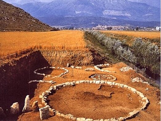 La necropoli di Campovalano, frazione di Campli (TE), rappresenta uno dei siti archeologici più rilevanti della provincia di Teramo. Situata su un terrazzo fluviale di circa cinquanta ettari, è attraversata da un'antica via lastricata, conosciuta come "Via Sacra". Gli scavi, iniziati nel 1967, hanno riportato alla luce oltre seicento tombe ad inumazione, databili dalla fine dell'Età del Bronzo fino alla conquista romana. Tuttavia, recenti ricerche ipotizzano la presenza di almeno ventimila sepolture ancora sepolte. I primi ritrovamenti, avvenuti casualmente, riguardano corredi funerari che riflettono la struttura sociale dell'epoca, suddivisa in classi a partire dal VII secolo a.C. Tra le sepolture più significative si distingue la tomba n. 100, che per dimensioni e ricchezza del corredo testimonia l'alto rango sociale del defunto. Il corredo include un carro da combattimento e servizi da mensa, elementi che richiamano la pratica del banchetto riservata all'aristocrazia. Un'iscrizione su tavoletta, prerogativa del pater familias, rappresenta non solo uno strumento di comunicazione, ma anche il simbolo del sapere del defunto. Il corpo era deposto supino, con le braccia lungo i fianchi e la testa adagiata su un ciottolo piatto utilizzato come cuscino. Le campagne di scavo condotte negli anni '60 e '70 da Valerio Cianfarani hanno portato alla luce tombe dell'Età Orientalizzante e Arcaica, mentre le ricerche degli anni '80 e '90 di Vincenzo D'Ercole hanno rivelato sepolture della fase italico-ellenistica. Il periodo di massimo splendore della necropoli si colloca tra l'VIII e il VI secolo a.C., con la costruzione di grandi tumuli circondati da pietre, il cui diametro varia dai quattro ai venticinque metri. I tumuli più piccoli, meglio conservati, erano destinati a sepolture infantili. Nel corso del primo millennio, l'organizzazione della necropoli subisce profonde trasformazioni. Dalla fase "monarchica", con tumuli disposti per nuclei familiari, si passa alla fase repubblicana con sepolture prive di corredo. In Età Ellenistica, le tombe a fossa sono orientate verso sud e contengono vasi di ceramica tornita, spesso verniciati in nero. Le sepolture femminili includono strumenti per la cura del corpo, mentre in quelle maschili le armi vengono sostituite dagli strigili e dai vasi porta sabbia, tipici dell'atleta. La necropoli rimase in uso fino agli inizi del II secolo a.C., quando la pianura tornò a essere destinata all'agricoltura.