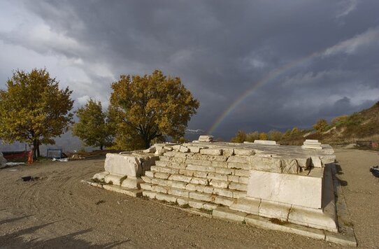 Il Santuario Italico di Schiavi d'Abruzzo, situato nel comune di Schiavi d'Abruzzo, in provincia di Chieti, è uno dei più significativi siti archeologici dell'Abruzzo. Risalente al II secolo a.C., questo santuario sannita sorge in località Colle della Torre, lungo la strada provinciale che da fondovalle Trigno sale verso il paese. L'area sacra, edificata su una terrazza naturale, fu inizialmente dotata di un grande tempio e di un muro di terrazzamento, che delimitava lo spazio sacro. L'uso del santuario si estese per diversi secoli, fino al IV secolo d.C., sebbene l'intensa attività si fosse ridotta già in epoca romana. Il santuario comprende due templi disposti parallelamente: il primo, di dimensioni maggiori, risale al III secolo a.C. ed era dedicato a riti di culto di grande importanza. Con un'area di 21x11 metri, il tempio maggiore si distingueva per le quattro colonne in pietra sul fronte e per il podio accessibile tramite una scalinata. Il fregio del tempio, decorato con lastre di terracotta, è uno degli elementi più interessanti emersi dagli scavi archeologici. Il secondo tempio, di dimensioni più ridotte, fu costruito agli inizi del I secolo a.C. e non presentava il podio, ma aveva comunque una grande rilevanza religiosa, come testimoniano le scoperte di un altare e di numerosi resti votivi nelle sue vicinanze. A partire dal XIV secolo, il santuario venne abbandonato a causa di un'importante frana che colpì l'area, segnando la fine della sua frequentazione. Tuttavia, il sito continuò a essere di interesse per gli archeologi, che nel corso degli anni hanno riportato alla luce diverse necropoli, tra cui una scoperta nel 1955, con tombe a cappuccina, e un'altra nel 1997, che ha rivelato sepolture risalenti tra il IX e il VI secolo a.C. Alcuni di questi reperti, tra cui ceramiche e materiali votivi, testimoniano una frequentazione del sito che si prolungò ben oltre la fine dell'era romana. Oggi, il Santuario Italico di Schiavi d'Abruzzo è uno dei luoghi di maggiore fascino storico e panoramico della regione. Situato a quasi mille metri d'altitudine, offre una vista spettacolare sulla vallata del fiume Trigno, che ne esalta ulteriormente la bellezza e l'importanza. La scoperta di strutture sacre, come il tempio minore con pavimenti in mosaico e iscrizioni in lingua osca, ha permesso di ricostruire parte della vita religiosa e sociale degli antichi abitanti di questa zona. Il sito, che conserva anche una torre medievale, rappresenta non solo un importante punto di riferimento per gli studiosi, ma anche una meta affascinante per i visitatori interessati alla storia e alla cultura dell'Abruzzo.
