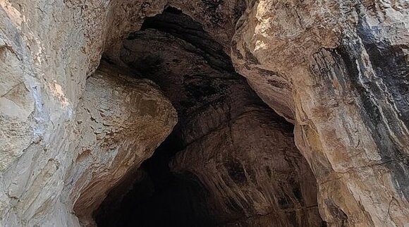 Le Grotte Naturali in Abruzzo. La Grotta Scura, situata nel territorio di Bolognano (PE) alle estremità settentrionali del Parco Nazionale della Majella, si trova a circa 300 metri di altitudine. Insieme alla vicina Grotta del Mortaio, rappresenta un importante sito archeologico, grazie ai ritrovamenti che testimoniano la presenza umana fin dal Neolitico. La sua conformazione geologica e la posizione panoramica sulla Valle dell'Orta la rendono una meta di grande fascino naturalistico e storico. Questa cavità carsica è il risultato dello scorrimento del fiume Orta a livelli superiori rispetto al corso attuale, configurandosi come un “fiume fossile”. La grotta si sviluppa per oltre 350 metri, con i primi cento metri accessibili autonomamente fino alle due camere iniziali illuminate. Da qui si dipartono cunicoli più profondi che conducono ad altre sale, la cui visita è consentita solo con l'accompagnamento di uno speleologo. Le aperture naturali sulle pareti permettono una circolazione d'aria che stabilizza la temperatura interna, creando un microclima particolare e limitando l'escursione termica con l'esterno. Gli studi archeologici, avviati negli anni Settanta del Novecento, hanno portato alla luce frammenti di vasellame in argilla, attestando l'uso della grotta tra il Neolitico e l'Età dei Metalli. Si ritiene che la cavità fosse utilizzata per rituali legati al culto dell'acqua, grazie alla presenza di vaschette carsiche formate dal gocciolamento. La funzione del sito è variata nel corso del tempo, adattandosi ai cambiamenti ambientali e alle esigenze delle popolazioni che l'hanno abitata. Durante la Seconda Guerra Mondiale, la grotta divenne rifugio per la popolazione locale, offrendo protezione dai bombardamenti. La sua posizione strategica la rese in seguito una base per una postazione di contraerea tedesca, destinata a contrastare gli aerei alleati impegnati nei bombardamenti dello stabilimento Montecatini di Piano d'Orta. Questi eventi hanno aggiunto un ulteriore strato di significato storico a un luogo già ricco di testimonianze archeologiche e naturali.