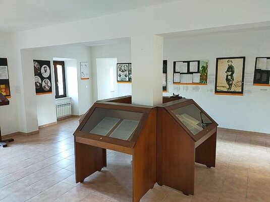 Il Museo del Brigantaggio e dell'Unità d'Italia, situato nel Palazzo Colelli di Sante Marie (AQ), racconta la storia di uno dei periodi più complessi e turbolenti della storia d'Italia, quello del brigantaggio post-unitario. La scelta di ospitare il museo in questo storico edificio settecentesco non è casuale: è proprio in queste terre che, nel dicembre del 1861, venne catturato il generale José Borjes, inviato da Francesco II di Borbone nelle regioni dell'ex Regno delle Due Sicilie per tentare di riconquistare i territori perduti. La cattura di Borjes avvenne grazie alla delazione di alcuni abitanti locali nella cascina Mastroddi, tra Sante Marie e Castelvecchio, e la sua morte, avvenuta poche ore dopo, segnò uno degli episodi emblematici della resistenza al nuovo Stato unitario. Nonostante la morte di Borjes, il brigantaggio continuò ad essere un fenomeno diffuso nelle zone della Marsica e del Cicolano almeno fino al 1870, quando la presa di Roma segnò simbolicamente la fine di questo movimento di resistenza. Il museo, inaugurato nel 2008, racconta non solo la storia della cattura e dell'esecuzione di Borjes, ma anche il contesto più ampio di una lotta che coinvolse molti altri briganti e le comunità locali che vi presero parte. L'allestimento museale, realizzato in collaborazione con l'Archivio di Stato dell'Aquila e la sezione di Avezzano, raccoglie numerosi documenti e reperti storici che testimoniano le dure vicende di un'epoca segnata dalla lotta tra il nuovo Regno d'Italia e le resistenze locali. La collezione del museo, arricchita anche grazie alle donazioni di cittadini, tra cui Gianvincenzo Sforza di Celano, offre un'ampia panoramica sugli eventi che caratterizzarono il brigantaggio, mettendo in luce non solo gli aspetti militari e politici, ma anche quelli sociali e culturali che ne furono alla base. Il museo si propone infatti di approfondire le radici di questo fenomeno, raccontando le storie di uomini e donne che, spesso contro la loro volontà, si trovarono coinvolti in una guerra civile che li segnò profondamente. Le esposizioni permettono ai visitatori di comprendere meglio come il brigantaggio fosse percepito dalle diverse comunità locali e come la lotta per la resistenza alla modernità e all'unità d'Italia divenisse un elemento centrale della loro identità. Il museo di Sante Marie rappresenta anche un importante punto di riferimento per il Cammino dei Briganti, inaugurato nel 2016, che attraversa i luoghi legati a questi eventi storici. Questo itinerario, che unisce storia e natura, permette ai visitatori di rivivere le tracce lasciate dal brigantaggio sul territorio, offrendo un'esperienza immersiva che si intreccia con la storia locale. Grazie al suo ruolo di conservazione della memoria storica e alla sua capacità di attrarre un pubblico di appassionati e studiosi, il Museo del Brigantaggio e dell'Unità d'Italia continua a essere una tappa fondamentale per chi desidera comprendere meglio il complesso processo di unificazione dell'Italia e le sue ripercussioni sulle popolazioni del sud.