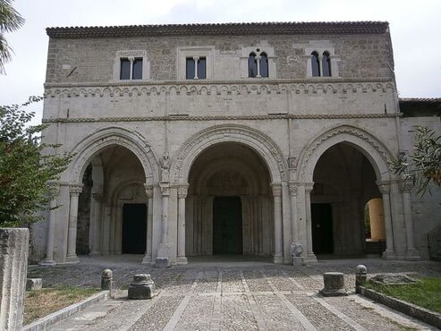 I luoghi sacri in Abruzzo: L’abbazia di San Clemente a Casauria. L'abbazia di San Clemente a Casauria, situata lungo la valle del fiume Pescara, è un luogo di culto di straordinaria importanza per la storia religiosa e spirituale dell'Abruzzo. Fondata nell'IX secolo, la chiesa originaria testimoniava fin da subito l’importanza di questo luogo come centro di devozione. Con il passare dei secoli, il sito ha conosciuto diversi momenti di distruzione e ricostruzione, ma non ha mai perso il suo ruolo di faro di fede per la regione. Il suo legame con la tradizione monastica e la spiritualità cristiana è stato sempre molto forte, attirando pellegrini e devoti che trovano in questo luogo una profonda serenità e riflessione. Nel corso dei secoli, l'abbazia è stata ricostruita e ampliata, assumendo la sua forma attuale nel XII secolo, quando fu ristrutturata in stile romanico. Ogni elemento architettonico dell'edificio riflette la grande importanza che il culto aveva in quel periodo, con particolare attenzione alla decorazione della facciata e alla creazione di uno spazio che potesse accogliere sia i monaci che i fedeli. La facciata, con i suoi tre portali e il portico, è una delle caratteristiche che più colpiscono, simbolo di una comunità che si apre al mondo pur mantenendo salde le proprie radici spirituali. Il cuore dell'abbazia è il suo interno, che conserva numerosi arredi sacri, tra cui l’ambone, il cero pasquale e il ciborio. Questi arredi, finemente scolpiti in pietra, non solo rappresentano un trionfo della maestria artigianale medievale, ma sono anche oggetti di profonda sacralità, utilizzati durante le celebrazioni liturgiche che scandivano la vita monastica. Il culto che si celebrava in questo spazio era quello tradizionale monastico, con la preghiera e il canto che univano la comunità dei monaci in un rapporto diretto con Dio. Oggi, l'abbazia di San Clemente a Casauria è ancora un centro di culto attivo, dove si celebrano funzioni religiose e momenti di raccoglimento. Ogni anno, numerosi fedeli e visitatori vengono a pregare e ad ammirare la bellezza del luogo, che continua a custodire una forte carica spirituale. Questo sito non è solo un esempio straordinario di arte medievale, ma anche un luogo che mantiene viva la tradizione di fede e spiritualità dell’Abruzzo, fungendo da punto di riferimento per chi cerca la pace interiore e un contatto più profondo con la propria fede.