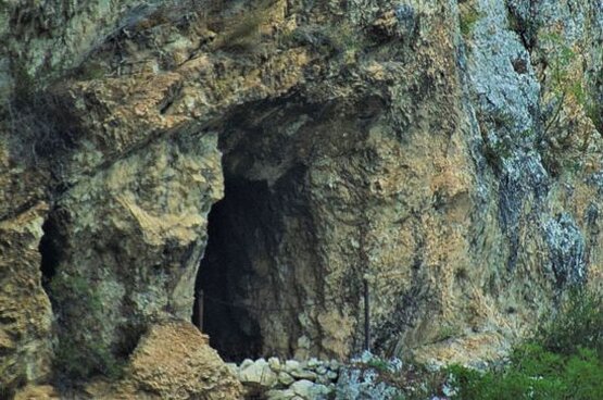 La Grotta di Placido da Roio si trova in una posizione solitaria e impervia, sulle pareti del Monte Circolo, nei pressi di Fossa, un piccolo paese della provincia aquilana. L’ingresso alla grotta è nascosto e difficile da individuare, tanto che non è visibile né dal paese né dalla base della montagna. È situata a una notevole altezza, raggiungibile solo percorrendo un canalino erboso che porta alla sua bocca. L'accesso è stato parzialmente ostruito negli ultimi anni a causa di un crollo, ma l'atmosfera rimane quella di un luogo lontano e isolato, che ha mantenuto inalterata la sua sacralità nel tempo. All'interno della grotta, le pareti sono rettilinee e alte circa cinque metri. Sul lato destro, si possono osservare segni di scalpello, nicchie e una canaletta che veniva utilizzata per raccogliere l'acqua piovana. Questi segni sono il frutto di un utilizzo umano antico, legato alla vita eremitica del Beato Placido da Roio, che decise di ritirarsi in questo luogo per dedicarsi completamente alla preghiera. La grotta si rivela così un luogo di meditazione e spiritualità, dove Placido visse in solitudine per dodici anni, cercando di avvicinarsi a Dio lontano dalle distrazioni del mondo. Placido da Roio nacque a Roio, nei pressi de L'Aquila, nella seconda metà del XIII secolo. Dopo un pellegrinaggio a San Giacomo di Compostela, e un lungo periodo di malattia che lo costrinse a rimanere disteso per circa cinque anni, decise di ritirarsi sui monti del Gran Sasso. Lì trovò rifugio nella grotta del Monte Circolo, dove visse come eremita. Durante questi anni di solitudine, la sua fama di santità crebbe, attirando numerosi seguaci. Quando la sua vita divenne nota, il conte Berardo di Ocre lo invitò a fondare un monastero in un luogo più facilmente accessibile, dando così vita al Monastero di San Spirito in Pretola. La tradizione racconta che Placido, dopo aver trascorso vent'anni a guidare la comunità del monastero, avvertì la morte imminente. Chiamò a sé l’abate Ruggero di Casanuova per confessarsi e per rendere formale l'aggregazione del monastero all'Ordine Cistercense. Placido morì il 13 giugno 1248, ma la sua figura continuò a vivere attraverso la comunità che aveva fondato. Oggi, la Grotta di Placido da Roio rimane un luogo di spiritualità e riflessione, che conserva il ricordo di un uomo che dedicò la sua vita alla preghiera e alla contemplazione in un angolo solitario del Gran Sasso.