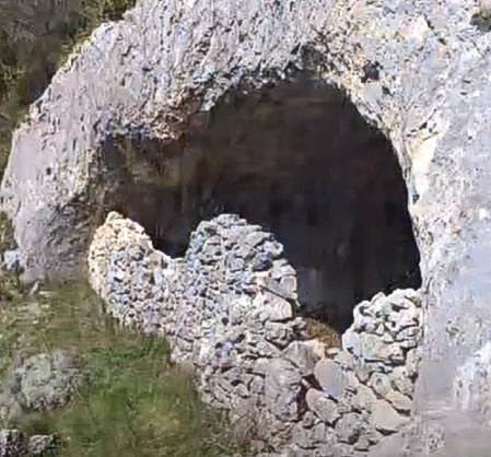 La Grotta Cavaliera, situata nel cuore della Maiella orientale, è un sito naturale di grande rilevanza, legato profondamente alla tradizione della transumanza, che caratterizzava la vita dei pastori abruzzesi. Questo rito antico prevedeva il trasferimento delle greggi dai pascoli bassi alle montagne più alte, un fenomeno che si ripeteva ogni anno, dalla primavera all'autunno. La grotta si trova nella Valle dell'Avello, attraversata dal fiume che dà il nome alla valle e che attraversa il comune di Pennapiedimonte, in una posizione che la rendeva perfetta per il rifugio dei pastori. La cavità si estende in due rami principali, uno dei quali attraversa la Valle delle Tre Grotte, mentre l'altro si inoltra nella Valle di Selvaromana. La Grotta Cavaliera è composta da tre stanze non comunicanti, con una di esse situata sopra la roccia che ospita la grotta stessa. Questa camera di grandi dimensioni è protetta da un muro a secco, mentre una piccola porta in legno permette l'accesso a una seconda stanza, più nascosta, conosciuta come "Grotta piccola della Cavaliera". L’atmosfera che si respira all’interno di questi ambienti è quella di un luogo che ha visto passare generazioni di pastori e che, con il suo silenzio, racconta le storie di vita montana. Il nome della grotta, che richiama la tradizione della pastorizia, è spesso associato anche alla denominazione di "Grotta di Sant'Anna", in quanto in tempi antichi si celebravano messe in suo onore da parte dei frati eremiti che vi si rifugiavano. La grotta, pur se relativamente isolata, ha sempre avuto un forte legame con la spiritualità e la religiosità locale, con una dimensione mistica che l’ha resa un punto di riferimento per chi cercava rifugio e meditazione. La storia di questo luogo è un intreccio di cultura popolare e di tradizioni religiose che si sono evolute nel corso dei secoli. Raggiungere la Grotta Cavaliera non è impresa facile, ma il percorso che parte dalla località Balzolo di Pennapiedimonte offre al visitatore un'esperienza unica. Dopo aver attraversato il Rifugio Pischioli e la Valle dell'Avello, il cammino giunge fino all'ingresso della grotta, dove il panorama che si apre dinanzi agli occhi è di una bellezza straordinaria. Da qui si può ammirare una vista mozzafiato che si estende fino all'Adriatico, con paesaggi naturali incontaminati e una sensazione di pace assoluta. La Grotta Cavaliera non è solo un sito naturale, ma un vero e proprio viaggio nella storia e nelle tradizioni della montagna abruzzese.