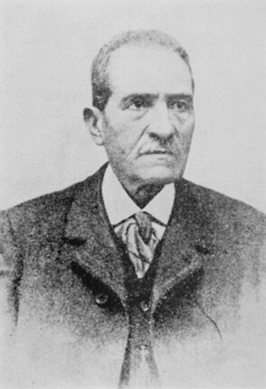 Antonio De Nino, figura centrale della cultura abruzzese, si distinse per il suo instancabile lavoro di antropologo, storico e archeologo. Nato a Pratola Peligna nel 1833, dedicò la sua vita alla documentazione e allo studio delle tradizioni popolari e del patrimonio archeologico della sua terra. La sua opera più celebre, “Usi e costumi abruzzesi”, pubblicata in sei volumi tra il 1879 e il 1897, rappresenta un ineguagliabile affresco della vita e delle tradizioni delle comunità abruzzesi, descritte con una rara combinazione di passione e metodo analitico. Con questo lavoro, De Nino pose le basi per uno studio critico e sistematico delle tradizioni popolari, influenzando profondamente la ricerca etnografica italiana. La passione di De Nino per l'archeologia lo portò a diventare uno dei pionieri delle moderne campagne di scavo in Abruzzo. Con il ruolo di Ispettore onorario ai Monumenti, condusse oltre cento campagne di scavo, portando alla luce reperti di inestimabile valore storico. Tra le sue scoperte più importanti vi furono la necropoli di Alfedena e i resti dell’antica Corfinium, capitale della Lega Italica durante la Guerra Sociale. A Corfinio rinvenne l’iscrizione di Herentas, una testimonianza fondamentale della lingua peligna, e contribuì a ricostruire la storia delle popolazioni italiche pre-romane. L’opera di De Nino non si limitò agli scavi, ma abbracciò anche la documentazione e la valorizzazione dei monumenti abruzzesi. Collaborò con importanti intellettuali del suo tempo, come Gabriele D’Annunzio e Francesco Paolo Michetti, fornendo supporto per la ricerca storica e le ambientazioni delle opere artistiche. Il suo contributo alle esplorazioni archeologiche e alla catalogazione dei siti monumentali abruzzesi fu decisivo per la costruzione di un’identità culturale regionale. La sua attenzione verso le epigrafi e i testi antichi lo rese un riferimento per studiosi internazionali, che apprezzarono il suo lavoro di trascrizione e interpretazione. Come educatore, De Nino lasciò un segno profondo nella sua comunità. Dopo aver lavorato come insegnante in diverse località, tornò a Sulmona, dove divenne direttore delle scuole regie secondarie. Qui fondò “La Gazzetta di Sulmona”, una pubblicazione in cui divulgò i risultati delle sue ricerche archeologiche e storiche. Attraverso la stampa, De Nino riuscì a sensibilizzare il pubblico sull'importanza della conservazione del patrimonio storico e culturale abruzzese, trasformando la sua attività in una missione educativa e sociale. L’eredità di Antonio De Nino vive ancora oggi nei musei, nelle biblioteche e nei luoghi che custodiscono i frutti del suo instancabile lavoro. Quattro musei archeologici abruzzesi portano il suo nome, a testimonianza del suo contributo alla valorizzazione del patrimonio regionale. La sua opera non solo ha reso l’Abruzzo una terra più consapevole delle proprie radici, ma ha anche ispirato generazioni di studiosi, lasciando un’impronta indelebile nella storia culturale italiana.