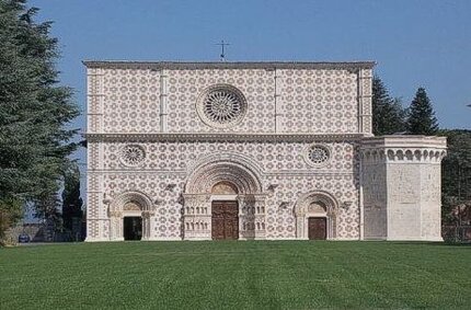La Basilica di Santa Maria di Collemaggio, situata a L'Aquila, è uno dei simboli più importanti della città e dell'Abruzzo. Fu fondata nel 1288 su iniziativa di Pietro Angelerio, il futuro Papa Celestino V, ed è celebre sia per la sua bellezza architettonica che per la sua importanza storica e spirituale. La basilica è un capolavoro che unisce stili romanico e gotico, con influenze tipiche dell'architettura locale. La facciata, rivestita in pietra bianca e rosa, si distingue per le sue decorazioni geometriche e il magnifico rosone centrale. I tre portali presentano dettagli scultorei raffinati, con il portale maggiore particolarmente elaborato. L'interno, a tre navate, è semplice ma suggestivo, e custodisce il mausoleo di Celestino V, dove riposano le spoglie del santo. La basilica è inoltre famosa per la Perdonanza Celestiniana, il giubileo annuale istituito da Celestino V nel 1294 con la Bolla del Perdono, che ogni anno attira numerosi pellegrini nei giorni del 28 e 29 agosto. Il terremoto del 2009 ha causato gravi danni alla basilica, con il crollo della volta e di altre parti strutturali. I lavori di restauro, terminati nel 2017, hanno restituito alla basilica il suo splendore, utilizzando tecniche moderne per garantire sicurezza e fedeltà storica. La Basilica di Collemaggio rappresenta oggi un luogo di grande significato, non solo per la sua rilevanza religiosa, ma anche come simbolo della resilienza della città dell'Aquila.