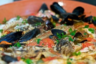 Per preparare il brodetto alla vastese, iniziate pulendo e sfilettando il pesce fresco, che può includere triglie, merluzzo, scorfano e altri pesci tipici della zona. È importante selezionare pesce fresco e di qualità, poiché sarà il protagonista del piatto. In una casseruola capiente, scaldate un filo di olio extravergine d'oliva e soffriggete le cipolle tritate finemente insieme agli spicchi d'aglio, che rilasceranno i loro aromi, creando una base profumata per il brodetto. Aggiungete quindi il peperoncino per un tocco di piccantezza e lasciate cuocere il soffritto fino a che la cipolla non diventa morbida e trasparente. A questo punto, aggiungete i pomodori pelati, precedentemente schiacciati con una forchetta, e mescolate bene il tutto. Il pomodoro contribuirà a dare dolcezza e acidità al sugo, bilanciando perfettamente la sapidità del pesce. Lasciate cuocere il pomodoro per circa 15 minuti, facendo attenzione che il sugo non si asciughi troppo, aggiungendo un po' di acqua o brodo di pesce se necessario. Una volta che il sugo è ben amalgamato, versate il vino bianco secco, che contribuirà a deglassare la pentola e aggiungere una nota fruttata, facendo evaporare l'alcol per un paio di minuti. Ora è il momento di aggiungere il pesce al sugo. A seconda del tipo di pesce utilizzato, aggiungetelo in ordine, iniziando con quello che richiede una cottura più lunga, come il merluzzo o lo scorfano. Cuocete a fuoco lento, coprendo la casseruola, in modo che il pesce si cuocia delicatamente, assorbendo i sapori del sugo e mantenendo la sua carne tenera. Dopo 20-30 minuti, aggiustate di sale e pepe e, se necessario, aggiungete un altro filo di olio extravergine d'oliva per arricchire il piatto di un sapore più intenso. Una volta che il pesce è cotto e il brodetto ha acquisito una consistenza densa e saporita, servite il piatto caldo, accompagnato da fette di pane casereccio abbrustolito. Il pane, che si impregnerà del sugo ricco, esalterà ulteriormente i sapori del brodetto, completando il piatto con una nota rustica. Il brodetto alla vastese è pronto per essere gustato, offrendo un mix perfetto di sapori del mare e aromi mediterranei, che lo rendono un piatto ideale per pranzi conviviali o occasioni speciali.