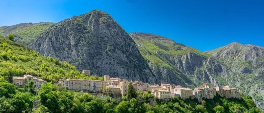 Borghi Medievali e Archeologia in Abruzzo: Castrovalva, il Borgo di Escher. Castrovalva, il Borgo di Escher. Castrovalva è un piccolo borgo che si erge solitario su una cresta rocciosa, nel cuore delle montagne abruzzesi. Situato tra Pratola Peligna e Cocullo, questo paese sembra quasi sfidare la gravità, con le sue case strette e aggrappate alla montagna, a strapiombo sul fiume Sagittario. Raggiungerlo non è semplice: la strada si arrampica tortuosa lungo il fianco della montagna, facendo di Castrovalva un luogo che non si visita per caso, ma solo dopo averlo cercato e desiderato. La sua posizione isolata lo rende un angolo nascosto della regione, lontano dalle rotte turistiche più battute, ma proprio per questo il suo fascino rimane intatto, lontano dal caos della modernità. Il nome Castrovalva deriva dal latino Castrum de Valva, un chiaro riferimento alla sua natura di borgo fortificato, che affonda le radici nell’antica diocesi di Valva. Oggi, il borgo conserva ancora tracce della sua struttura difensiva, visibili nelle case costruite con muri spessi e compattezza tipica dei luoghi destinati alla protezione. La strada che conduce al borgo, stretta e tortuosa, attraversa paesaggi mozzafiato, offrendo uno spettacolo di natura selvaggia. Chi arriva a Castrovalva non può fare a meno di percepire l'energia di un luogo che ha resistito al passare del tempo, rimanendo praticamente immutato nei secoli. Un grande protagonista della storia di Castrovalva è l’artista olandese Maurits Cornelius Escher, che più di ottant’anni fa visitò il borgo e ne rimase profondamente colpito. La sua visita portò alla creazione di una delle sue litografie più celebri, che ritrae Castrovalva con una prospettiva impossibile e vertiginosa, in cui le case sembrano emergere dalla montagna come se fossero parte integrante della roccia. Escher non si limitò a rappresentare il luogo, ma lo trasformò in un’idea, usando la sua tecnica unica per esaltare il contrasto tra realtà e percezione, un tema ricorrente nella sua arte. La sua visione del borgo è un gioco tra il reale e il surreale, dove la montagna diventa metafora di una dimensione intangibile e misteriosa. Oggi, Castrovalva è molto più di un luogo famoso per la sua bellezza scenografica e la sua storia legata a Escher. Il borgo, con la sua posizione isolata, offre anche un senso di pace e tranquillità che invita alla riflessione. Camminando per le sue strade, si respira una quiete che ricorda gli eremi nascosti della Majella o le abbazie benedettine immerse nel verde. Castrovalva non è solo un angolo remoto e affascinante del nostro passato, ma un luogo che porta con sé un’atmosfera di sacralità e di ritorno a un tempo più semplice, dove la natura e l’uomo sembrano ancora convivere in armonia.