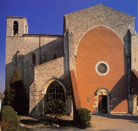 L’Abbazia di Santa Maria Arabona a Manoppello Scalo (Pe) Chiesa di Santa Maria Arabona a Santa Maria Arabona di Manoppello (Pe) Santa Maria Arabona è un'abbazia risalente alla fine dell'XII secolo che si trova nell'omonima frazione in comune di Manoppello (PE). La Storia della Chiesa di Santa Maria Arabona a Santa Maria Arabona di Manoppello (Pe) Su un'area, in cima ad una collina, da dove si domina parte della vallata del Pescara, dedicata ai tempi dei Romani al culto della Bona Dea (e forse da questo deriva il termine "Arabona"), sul quale esisteva un tempio pagano, andato distrutto, che ha fornito una parte dei materiali con cui è stata realizzata l'abbazia che i Cistercensi cominciarono nel 1197, dedicando la chiesa abbaziale in costruzione, alla Vergine Maria; ancora oggi è possibile notare alcune strutture e pietre del preesistente tempio romano. L'edificazione della Chiesa di Santa Maria Arabona a Santa Maria Arabona di Manoppello fu iniziata dalla parte absidale e dal transetto, poiché la navata centrale, interrotta all'altezza della seconda campata, risulta essere anteriore di almeno mezzo secolo alla sua prosecuzione verso la facciata. La mancanza di gran parte del piedicroce è giustificata dall'abbandono del progetto iniziale e dalla conclusione affrettata dei lavori, forse per le avvisaglie di un decadimento economico e strategico all'interno della politica dell'ordine. Nei primi anni cinquanta la Chiesa di Santa Maria Arabona a Santa Maria Arabona di Manoppello fu sottoposta a restauri che si conclusero con la riapertura al culto il 25 settembre 1952 alla presenza del Presidente della Repubblica Italiana Luigi Einaudi. La famiglia Zambra, proprietaria dell'abbazia sin dal 1799, dopo la morte del loro unico figlio Dino Zambra, avvenuta il 3 gennaio 1944 durante la Seconda guerra mondiale, nel 1968 la donò alla congregazione dei Salesiani. Dal 1998, l'abbazia è sotto il diretto controllo dell'Arcidiocesi di Chieti-Vasto. L’Architettura della Chiesa di Santa Maria Arabona a Santa Maria Arabona di Manoppello (Pe) Di impianto semplice a croce latina, la chiesa si sviluppa soprattutto nella navata centrale che si conclude con l'abside, nella cui apertura è posto l'altare. La chiesa è circondata da un parco dal quale si accede al corpo restante dell'abbazia. Le navate laterali sorreggono l'intera volta e gli altari sono disposti lungo il transetto. L'interno è caratterizzato inoltre dalla presenza delle costolature che danno slancio ai volumi e sottolineano le luci degli archi e le fughe delle volte. In mezzo ad uno spazio sobrio e lineare spicca la ricchezza degli arredi costituiti dal tabernacolo e dal candelabro. Il tabernacolo è formato da un'edicola gotica finemente lavorata, che appoggia al muro; il cero si innalza con un'aerea leggerezza su una snella colonnina, sostenuta da due cani e da un leone rampante. Tre dipinti firmati da Antonio Martini di Atri e datati al 1377, decorano la parete del coro: rappresentano, nell'ordine, una Santa coronata, una Crocifissione e una Vergine in trono con Bambino, che a sua volta tiene tra le mani un piccolo cane bianco. All'interno dell'abbazia è presente una cappella dedicata all'Ordine equestre del Santo Sepolcro di Gerusalemme usata dalla "Sezione Abruzzo e Molise" dell'ordine. Il candelabro della Chiesa di Santa Maria Arabona a Santa Maria Arabona di Manoppello (Pe) Il candelabro per il cero pasquale è costituito principalmente da una colonna, rappresentante Gesù; attorno ad essa è intrecciata una vite, simbolo dei fedeli che traggono nutrimento dall'Eucarestia, che sfocia nel capitello decorato dalle sue foglie. Il tutto poggia su una base quadrata sulla quale alcuni animali (due cani e un leone – l’altro è mancante) attaccano alle radici la vite: rappresentano le eresie, che minacciano la fede e i cristiani. Il capitello è sovrastato invece da dodici colonnine (rappresentanti i dodici apostoli) disposte a base esagonale su due piani. Il candelabro termina infine con una colonna decorata a palmette dove riporre il cero benedetto il Sabato Santo. Il tabernacolo della Chiesa di Santa Maria Arabona a Santa Maria Arabona di Manoppello (Pe) Il tabernacolo è quasi attaccato alla parete dalla parte sinistra del coro ed è sorretto da due colonnine dalla parte opposta. È basato su una struttura a parallelepipedo; gli spigoli sono decorati da colonnine finemente lavorate con motivi ad intreccio mentre le facce sono decorate con motivi floreali. La parte superiore, danneggiata, è sormontata da due piccole guglie.