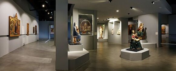 Museo Nazionale d'Abruzzo (MuNDA) - L'Aquila Il Museo Nazionale d'Abruzzo (MuNDA), situato nella città di L'Aquila, rappresenta una delle più importanti istituzioni culturali della regione. Fondato con l'obiettivo di preservare e valorizzare il patrimonio artistico e storico dell'Abruzzo, il museo è stato originariamente ospitato nel celebre Forte Spagnolo. A seguito del devastante terremoto del 2009, il MuNDA ha subito una significativa trasformazione, trovando una nuova collocazione in una struttura moderna e accogliente che ne riflette l'importanza per la comunità locale e internazionale. Il percorso espositivo del MuNDA si distingue per la sua ricca collezione, che spazia dall'archeologia all'arte medievale, rinascimentale e barocca. Tra i pezzi più significativi si trovano opere come il celebre Trittico di Beffi, una raffinata testimonianza della pittura tardogotica, e la statua di San Sebastiano di Silvestro dell'Aquila, espressione dell'arte rinascimentale locale. Accanto a queste, il museo espone reperti archeologici che raccontano la storia delle popolazioni che hanno abitato l'Abruzzo fin dall'antichità. Un elemento distintivo del MuNDA è la sua attenzione all'accessibilità e all'innovazione tecnologica. L'allestimento è concepito per offrire un'esperienza immersiva, con l'uso di supporti multimediali che permettono ai visitatori di approfondire la conoscenza delle opere e del contesto storico in cui sono state realizzate. Questa impostazione moderna rende il museo un luogo dinamico, adatto non solo agli studiosi e agli appassionati d'arte, ma anche alle famiglie e ai giovani. Oltre alla sua funzione espositiva, il MuNDA è un centro attivo di ricerca e promozione culturale. Organizza regolarmente mostre temporanee, convegni e laboratori didattici per avvicinare il pubblico alle bellezze dell'Abruzzo. La sua presenza a L'Aquila rappresenta un simbolo di rinascita e resilienza per una città che ha saputo trasformare il dolore del terremoto in un'opportunità di crescita e rinnovamento culturale.