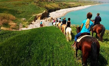 Ippovia della Costa dei Trabocchi. Un viaggio a cavallo tra scogliere e spiagge incantevoli. L'Ippovia della Costa dei Trabocchi offre un'esperienza unica a cavallo lungo uno dei tratti di costa più affascinanti d'Abruzzo. Partendo dal maneggio nei pressi di Punta Penna, il percorso si snoda attraverso sentieri panoramici immersi nella natura, regalando viste spettacolari sul mare e sulla celebre Riserva Naturale di Punta Aderci. Il primo tratto conduce attraverso una vegetazione lussureggiante, con il profumo della macchia mediterranea che accompagna i cavalieri lungo il cammino. Proseguendo verso il mare, si arriva alla scogliera di Punta Aderci, uno dei punti più suggestivi dell'intero itinerario. Qui il panorama si apre su acque cristalline e sulle caratteristiche calette, dove il paesaggio richiama immagini di terre lontane come l'Irlanda e l'Australia. La vista del Trabocco, antica macchina da pesca simbolo della costa, aggiunge un tocco di fascino e tradizione a questa esperienza immersiva nella natura incontaminata. Dalla scogliera si prosegue lungo un sentiero che costeggia la spiaggia di Mottagrossa, una distesa di ciottoli e sabbia dorata che si estende fino all'orizzonte. Il suono delle onde e la brezza marina rendono il tragitto ancora più suggestivo, offrendo un momento di pace e connessione con l'ambiente circostante. Il cavallo si muove con sicurezza su questo terreno variegato, permettendo di godere appieno della bellezza selvaggia della costa. Il percorso continua tra dolci saliscendi fino a ricongiungersi con l’entroterra, attraversando tratti di campagna e piccole zone boschive. Il contrasto tra il verde intenso della vegetazione e l'azzurro del mare crea un'atmosfera magica, mentre il profumo della salsedine accompagna ogni passo. Questo tratto offre anche la possibilità di avvistare diverse specie di fauna locale, rendendo l'escursione ancora più emozionante per gli amanti della natura. Dopo circa un'ora e mezza di cavalcata, il percorso si conclude con il ritorno al maneggio, lasciando nei partecipanti il ricordo di un'esperienza unica, tra panorami mozzafiato e il ritmo rilassante del cavallo. L'Ippovia della Costa dei Trabocchi è il modo perfetto per scoprire la bellezza di questo angolo d'Abruzzo in maniera autentica e suggestiva, vivendo una giornata all'insegna della natura e della tradizione.
