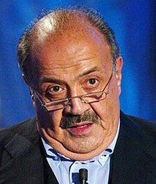 Maurizio Costanzo, nato a Roma il 28 agosto 1938 e scomparso il 24 febbraio 2023. Maurizio Costanzo è stato uno dei protagonisti più influenti della televisione e del giornalismo italiano, un innovatore capace di trasformare il panorama culturale del Paese. La sua attività professionale, iniziata come giornalista negli anni Cinquanta, lo vide rapidamente emergere come figura di riferimento nei media italiani. Dopo i primi passi presso il quotidiano Paese Sera, assunse il ruolo di caporedattore della rivista Grazia, dimostrando una precoce abilità nel raccontare storie e nel dirigere progetti editoriali. Parallelamente, iniziò a collaborare con la radio, un mezzo che lo accompagnò per tutta la sua carriera, ponendolo in contatto diretto con il pubblico. Il suo contributo più significativo è però legato alla televisione, dove divenne un autentico pioniere del talk show. Con programmi come Bontà loro, introdusse un nuovo modo di fare televisione, incentrato sul dialogo e sulla riflessione. Questa esperienza fu il preludio alla creazione del celebre Maurizio Costanzo Show, il talk show più longevo della storia italiana, registrato al Teatro Parioli di Roma. Il programma non fu solo uno spazio di intrattenimento, ma un vero e proprio laboratorio culturale, capace di dare voce a intellettuali, artisti, politici e personaggi emergenti, contribuendo a modellare il dibattito pubblico per decenni. Costanzo si distinse anche come scrittore e autore, collaborando con il cinema e il teatro. Scrisse numerose sceneggiature, tra cui quella per il film Una giornata particolare di Ettore Scola, e testi teatrali che riflettevano il suo interesse per le dinamiche sociali e familiari. Inoltre, la sua attività di paroliere lo portò a firmare testi indimenticabili, come la canzone Se telefonando, resa immortale dalla voce di Mina. La sua versatilità lo rese una figura poliedrica, capace di spaziare tra generi e linguaggi diversi, sempre con un approccio innovativo e profondo. Oltre alla sua presenza in televisione, Costanzo fu anche un imprenditore della comunicazione, dirigendo testate come La Domenica del Corriere e L’Occhio, e lavorando come consulente per la costruzione dell’immagine di personaggi pubblici. La sua competenza lo portò a ricoprire ruoli di responsabilità presso Mediaset, dove contribuì alla crescita del network. Anche in radio, con trasmissioni come L’uomo della notte, continuò a esplorare nuovi linguaggi, intrecciando attualità, riflessioni e dialoghi con il pubblico. L’attività di Maurizio Costanzo è stata sempre guidata da un’instancabile curiosità e dalla volontà di innovare. Attraverso la sua capacità di comunicare e di creare spazi di confronto, ha influenzato generazioni di giornalisti e conduttori, lasciando un’eredità culturale che va ben oltre il mondo dello spettacolo. La sua figura, legata alle radici abruzzesi della sua famiglia, rappresenta un esempio di come l’eccellenza possa emergere grazie al talento, alla dedizione e a una visione chiara del ruolo dei media nella società.