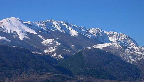 Il mare e la montagna in Abruzzo: Il monte Sirente. Il monte Sirente, una delle cime più affascinanti e imponenti dell’Abruzzo, si erge con la sua bastionata rocciosa che si estende per circa dieci chilometri sul versante settentrionale. Questo massiccio, dalle forme selvagge e spettacolari, è caratterizzato da profondi canaloni e speroni rocciosi che raggiungono anche i seicento metri di altezza. Con una geografia che alterna pareti verticali e solchi incisi nel tempo, il Sirente offre un paesaggio mozzafiato che incanta chiunque si avventuri alla sua scoperta. Il dislivello che separa i Prati del Sirente, un'area tranquilla e ricca di vegetazione, dalla sommità della montagna, che raggiunge i 2358 metri, è impressionante. La salita alla vetta è lunga e impegnativa, percorrendo sentieri che si snodano tra il bosco e i pascoli, ma la fatica viene ripagata da panorami incredibili. La roccia friabile e la qualità a volte insicura del terreno rendono l’ascesa più difficile, ma il fascino di questo luogo incontaminato attira ancora molti escursionisti. Durante i mesi invernali, quando il monte Sirente è ricoperto da una spessa coltre di neve, la montagna si trasforma in un paradiso per gli sciatori e gli appassionati di alpinismo. Il canalone Maiori, il più ampio della parete rocciosa, diventa una meta ambita, con centinaia di sciatori-alpinisti che lo risalgono e lo discendono, affrontando la montagna in condizioni particolarmente sfidanti. La bellezza di questo paesaggio invernale, con la neve che avvolge ogni angolo, regala un’esperienza unica. Il monte Sirente è un luogo che offre emozioni in ogni stagione, con i suoi panorami spettacolari e la natura incontaminata. Nonostante le difficoltà che presenta, la montagna è una delle mete più affascinanti dell'Abruzzo per chi ama l'avventura, il trekking e gli sport invernali, ma anche per chi cerca un contatto autentico con la natura. Ogni angolo del Sirente racconta una storia di natura selvaggia, rendendolo un vero e proprio tesoro della regione.