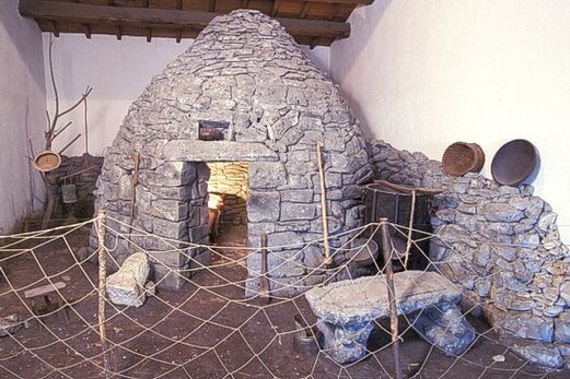 Musei e Raccolte in Abruzzo: Museo delle Genti d'Abruzzo – Pescara. Il Museo delle Genti d'Abruzzo, situato nel cuore della storica Pescara, all’interno delle antiche caserme borboniche, racconta la lunga e affascinante storia della regione. Il museo traccia l'evoluzione dell’uomo in Abruzzo, partendo dalle origini preistoriche, come cacciatore paleolitico, per arrivare fino alla meccanizzazione dei processi produttivi nel XIX secolo. Il tema centrale del museo è la continuità culturale, che esplora come le tradizioni, i mestieri, le credenze e i saperi tecnici abbiano attraversato i secoli e giunto intatti fino a noi, plasmando la società contemporanea. L’allestimento, ricco di diorami, ricostruzioni ambientali e postazioni multimediali, offre una visione immersiva delle tradizioni abruzzesi, con una particolare attenzione anche alla galleria fotografica che documenta il territorio attraverso il tempo. Le 15 sale espositive del museo si suddividono in diverse sezioni, ognuna delle quali racconta un aspetto diverso della storia abruzzese. Dalle sale archeologiche che esplorano i primi insediamenti e la cultura materiale delle antiche popolazioni, alle sale etnografiche che riflettono le tradizioni popolari, il museo offre una panoramica completa dell’evoluzione sociale e culturale della regione. In particolare, l’allestimento evidenzia come, nel corso dei secoli, molte pratiche quotidiane, come i luoghi di culto, le produzioni artigianali e i costumi, siano sopravvissuti nel tempo, testimoniando la tenacia delle tradizioni locali. All’interno del percorso, uno degli aspetti più affascinanti è la sezione dedicata alla preistoria, con particolare rilievo alle sepolture neolitiche di Villa Badessa, rinvenute a Rosciano. I corredi tombali e la posizione fetale dei defunti raccontano molto delle credenze e della vita delle prime popolazioni dell'Abruzzo. Inoltre, la sezione etnografica, che comprende usi e costumi, espone l’abito nuziale di Scanno, un raro esempio di sartoria tradizionale abruzzese risalente al XVIII secolo. Quest’abito, perfettamente conservato, diventa simbolo di una cultura che ha mantenuto viva la propria identità anche attraverso l’arte del vestire e delle tradizioni familiari. Il Museo delle Genti d'Abruzzo si distingue per la sua capacità di combinare la storia materiale con la storia immateriale, permettendo al visitatore di comprendere le radici profonde della comunità abruzzese. Grazie all’accurato allestimento e alla presenza di sezioni interattive, il museo non solo preserva ma rende vivide e coinvolgenti le storie delle genti che hanno abitato questa terra. Un viaggio che attraversa epoche e tradizioni, mettendo in luce l’importanza della memoria e della cultura per la costruzione dell’identità regionale.