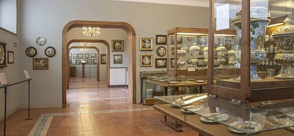 La Collezione Acerbo di Loreto Aprutino è un'importante testimonianza della tradizione ceramica di Castelli, ospitata in un museo che raccoglie una delle più prestigiose collezioni di maioliche della zona. La collezione, donata dal barone Giacomo Acerbo, è composta da circa 570 ceramiche, quasi tutte prodotte a Castelli tra la metà del XVI e il XIX secolo. Questo nucleo di opere rappresenta una straordinaria evoluzione dello stile ceramico di Castelli, dal Manierismo al Neoclassicismo, ed è una delle più complete testimonianze di questo tipo di arte nella regione. Un aspetto particolarmente interessante della collezione è il focus sul periodo barocco, quando Castelli raggiunse il culmine della sua produzione ceramica. Durante questa fase, la città diventò uno dei principali centri di produzione di maiolica del Regno di Napoli, con la sua arte che si diffuse anche nei centri ceramici italiani più importanti. Le opere esposte evidenziano l’eccellenza artistica dei più noti ceramisti castellani dell’epoca, tra cui le dinastie dei Grue, dei Gentili, dei Cappelletti e dei Fuina, che contribuirono a rendere Castelli famoso in tutta Italia e all'estero. Il percorso espositivo, che si snoda su più sale, non solo esplora la produzione di Castelli, ma presenta anche opere provenienti da altri importanti centri ceramici italiani come Faenza, Deruta, Roma e Napoli. Questi oggetti arricchiscono la raccolta, evidenziando l'influenza reciproca tra le diverse scuole ceramiche italiane. Tra le opere più significative, si trovano calamai, piatti istoriati, vasi da console e mattonelle che raccontano l'evoluzione del gusto e delle tecniche decorative dall'epoca rinascimentale al periodo barocco e neoclassico. Tra le opere più pregevoli, si distingue un calamaio del 1588, dipinto nello stile compendiario tipico di Castelli, e alcuni grandi piatti decorati con scene istoriate da Francesco Grue. Inoltre, il museo ospita il rinfrescatoio del XVII secolo decorato con episodi della vita del re David, realizzato nella bottega Grue, una delle opere di maggior valore della collezione. Il museo custodisce anche esempi significativi della maiolica di Gesulda Fuina, una ceramista che, nel XVIII e XIX secolo, innovò la tradizione ceramica castellana introducendo l'uso di colori vivaci, ottenuti con una terza cottura.