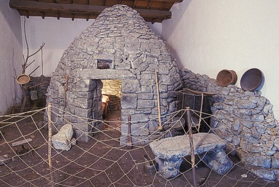 Il Museo delle Genti d’Abruzzo, situato nel cuore della vecchia Pescara all’interno delle antiche caserme borboniche, racconta la storia della regione dall’epoca preistorica fino agli sviluppi industriali del XIX secolo. Con un focus sulla continuità culturale, il museo esplora come tradizioni, tecniche e credenze siano state tramandate attraverso i secoli, dalle prime tracce di insediamenti umani alle trasformazioni sociali e produttive che hanno segnato l’epoca moderna. Le 15 sale espositive si snodano attraverso un percorso che unisce l’archeologia e l’etnografia, offrendo al visitatore una panoramica completa delle radici storiche, culturali e sociali dell’Abruzzo. L’allestimento del museo è arricchito da diorami, ricostruzioni ambientali, postazioni multimediali e una galleria fotografica che testimonia la bellezza e le tradizioni del territorio. Grazie a queste risorse, il museo riesce a trasmettere in modo coinvolgente la storia della regione, dalle prime comunità preistoriche alle trasformazioni moderne. Tra le tematiche trattate, il museo include anche il Risorgimento in Abruzzo, il Bagno Penale di Pescara e una sezione dedicata a Giuseppe di Prinzio, offrendo una visione completa delle vicende storiche che hanno caratterizzato la regione. Particolarmente significative sono le sepolture neolitiche rinvenute nella zona di Villa Badessa, una testimonianza unica delle pratiche funerarie e delle credenze religiose preistoriche. La sezione etnografica, invece, accoglie il famoso abito nuziale di Scanno, datato XVIII secolo, che si presenta integro e perfettamente conservato, offrendo uno spunto di riflessione sulle tradizioni sartoriali abruzzesi. Questi oggetti sono esposti in modo da evocare il legame profondo tra la popolazione abruzzese e il proprio territorio, le sue radici culturali e la sua storia. Inoltre, il museo promuove un’esperienza didattica e educativa che consente ai visitatori di entrare in contatto con il passato in modo interattivo, grazie a un allestimento innovativo e coinvolgente. Le sue collezioni non solo conservano ma celebrano la memoria storica dell’Abruzzo, rendendo il museo un punto di riferimento fondamentale per chi desidera comprendere l’evoluzione sociale, culturale ed economica della regione, dalle sue origini più remote fino alla modernità.