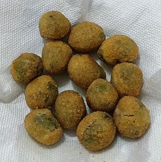 La preparazione delle olive farcite all’ascolana, un piatto che unisce sapientemente tradizione e territorialità, si basa su ingredienti tipici della cucina abruzzese. Le olive, preferibilmente della varietà ascolana tenera, rappresentano il cuore della ricetta. Questi frutti, coltivati nelle aree collinari della Val Vibrata, si distinguono per la loro polpa carnosa e il sapore dolce, che li rende perfetti per accogliere il ripieno. Il primo passo della preparazione consiste nella denocciolatura delle olive, un’operazione che richiede manualità e precisione, eseguita seguendo il tradizionale taglio a spirale per garantire che la forma del frutto rimanga intatta. Il ripieno è il segreto dell’unicità di questa ricetta. A base di carne bovina, suina e una piccola percentuale di pollo o tacchino, viene insaporito con parmigiano, noce moscata e una lieve nota di chiodi di garofano, spezie che richiamano la tradizione contadina abruzzese. Le carni, cotte a fuoco lento con cura, vengono successivamente tritate finemente e mescolate con il formaggio, creando un impasto morbido e aromatico. Questo composto viene inserito manualmente all’interno delle olive, una ad una, con un gesto paziente che testimonia l’artigianalità del piatto. Una volta farcite, le olive passano alla fase della panatura, un passaggio fondamentale per garantire una consistenza croccante. Ogni oliva viene prima infarinata, poi immersa nell’uovo sbattuto e infine ricoperta di pangrattato. Questa tripla panatura sigilla il ripieno all’interno, mantenendolo morbido durante la cottura e creando quella crosta dorata e friabile che rende le olive farcite irresistibili. La frittura avviene in abbondante olio caldo, rigorosamente extravergine d’oliva, altro elemento distintivo della tradizione abruzzese, che conferisce al piatto un profumo intenso e una leggerezza sorprendente. Le olive farcite, una volta fritte, vengono lasciate riposare brevemente per assestare i sapori e raggiungere la temperatura ideale per essere gustate. Ogni morso racconta una storia di semplicità e ricchezza, unendo la dolcezza della polpa d’oliva, la sapidità del ripieno e la croccantezza della panatura. Questo piatto, pur affondando le radici nella cucina povera, esalta i prodotti tipici della terra abruzzese con una maestria che lo rende un simbolo della tradizione culinaria locale. Le olive farcite all’ascolana continuano a essere protagoniste indiscusse delle tavole festive, portando con sé il sapore autentico della storia e della cultura di una regione.