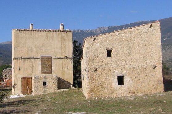 Castelli, fortificazioni e dimore in Abruzzo: Ofena e le “Pagliare”. Il centro medievale di Ofena, antica Aufinum, si trova in una posizione strategica alla base di una delle principali vie della transumanza, che conduce verso Castel del Monte e Campo Imperatore. Il borgo conserva un centro storico ben integrato, con stradine strette che invitano alla scoperta e chiese di grande interesse storico e artistico, testimoniando l'antico splendore della zona. Passeggiare tra i suoi vicoli offre una panoramica di un luogo che ha mantenuto intatta la sua anima medievale, dove ogni angolo racconta storie di un passato legato alla vita rurale e alle tradizioni secolari della regione. A monte di Ofena, si possono raggiungere i pittoreschi borghi di Garrufo e Villa Santa Lucia, che continuano a conservare il fascino dei villaggi montani. Garrufo, in particolare, si distingue per la sua impronta medievale, con case in pietra e viottoli che rievocano la semplicità della vita di un tempo. A valle, invece, si apre un panorama che culmina nel pianoro dove si trova il complesso delle “pagliare”, un antico borgo agricolo che un tempo ospitava le famiglie che si spostavano stagionalmente per lavorare i campi. Le pagliare erano abitate solo in estate, quando venivano sfruttate per l’allevamento e le coltivazioni agricole. Il complesso delle pagliare si distingue per le sue abitazioni costruite in pietra, perfettamente integrate nel paesaggio montano circostante. Ogni edificio racconta una storia di adattamento e resilienza, rispecchiando l’intima connessione tra gli abitanti e la terra che li ospitava. Le case di pietra e le strutture agricole, oggi abbandonate, sono un’affascinante testimonianza della vita rurale di un tempo, che era caratterizzata da un forte legame con la natura e dal ritmo delle stagioni. La camminata verso le pagliare, che può essere affrontata a piedi o in bicicletta, offre una panoramica unica del territorio, fatto di campi, pascoli e panorami mozzafiato. La passeggiata verso il borgo abbandonato delle pagliare inizia dalla chiesa di San Pietro ad Cryptis, situata a valle del paese. Questo luogo di culto, che ancora conserva la sua bellezza e il suo fascino, segna l'ingresso a un mondo antico e intatto, dove la natura e la storia si fondono in un'armonia perfetta. Il percorso permette di immergersi completamente nel paesaggio dell’Abruzzo, tra i vigneti che producono alcuni dei migliori vini rossi della regione, i boschi che si estendono intorno e le terre che, un tempo, sostenevano la vita di queste piccole comunità montane. Ofena e le sue pagliare offrono un’esperienza autentica, lontana dal turismo di massa, dove è possibile vivere la vera essenza di questa affascinante regione.