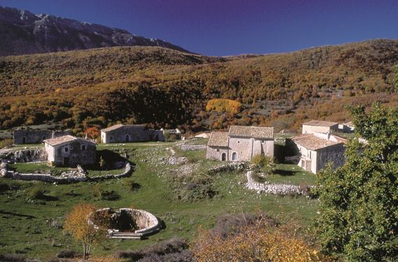 Castelli, fortificazioni e dimore in Abruzzo: Le Pagliare di Tione, Fontecchio e Fagnano. Le Pagliare di Tione, Fontecchio e Fagnano sono tre piccoli villaggi montani che offrono uno spaccato della tradizione agro-pastorale dell'Abruzzo. Questi borghi, un tempo abitati principalmente durante la stagione estiva, accoglievano le famiglie provenienti dai paesi sottostanti, che si trasferivano nelle alte terre per dedicarsi al lavoro nei campi e alla cura degli animali. Le case, costruite in pietra calcarea, si integrano perfettamente nel paesaggio montano, dando vita a un’atmosfera unica, lontana dal frastuono della vita quotidiana. Le Pagliare di Tione, le più celebri, si trovano su uno sperone roccioso e offrono una vista straordinaria sui pascoli sottostanti e sulla maestosa parete del Sirente. Il piccolo borgo di Tione è particolarmente noto per il suo grande pozzo circolare, che rappresenta una risorsa fondamentale per gli abitanti e simbolizza l’autosufficienza del luogo. La struttura delle case, con tetti in paglia e pietra a vista, rivela una perfetta simbiosi con l’ambiente naturale circostante. Sebbene le Pagliare di Tione siano le più visitate, anche Fontecchio e Fagnano non sono da meno in termini di fascino. Questi borghi, più appartati e meno frequentati, offrono una vista intima del paesaggio e un'atmosfera che conserva il carattere e la serenità di un tempo. In ogni angolo di questi villaggi si respira la storia di una vita che, pur cambiando, conserva ancora la sua essenza nelle architetture e nei paesaggi. Oltre alla loro bellezza paesaggistica, i villaggi delle Pagliare sono un punto di partenza ideale per chi ama l’avventura all’aria aperta. La zona circostante è perfetta per escursioni a piedi, a cavallo e in mountain bike, che permettono di scoprire i sentieri montani, i boschi e i panorami spettacolari che circondano i villaggi. Durante l’inverno, l’area si trasforma in un paradiso per gli sport invernali, con escursioni in sci da fondo o con le racchette da neve che offrono una nuova prospettiva del paesaggio, immerso in un silenzio incantevole e affascinante. Le Pagliare di Tione, Fontecchio e Fagnano non sono solo luoghi di grande bellezza naturale, ma anche custodi di una tradizione millenaria che racconta la vita semplice e rurale di un tempo. Questi borghi rappresentano un angolo autentico dell'Abruzzo, dove il passato si intreccia con il presente, creando un'esperienza unica per chi desidera riscoprire il ritmo lento e le tradizioni del territorio. La loro posizione isolata e la loro storia ne fanno una meta ideale per chi cerca tranquillità e un legame profondo con la natura.