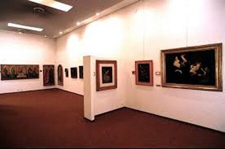 La Pinacoteca Civica di Teramo è uno dei principali presidi culturali della città e rappresenta il cuore pulsante del Polo Museale cittadino. Situata in posizione strategica, tra la Villa Comunale e le vie che conducono al centro storico, la Pinacoteca si inserisce armoniosamente nel tessuto urbano come un ponte ideale tra lo spazio naturale del giardino pubblico e l’anima storica della città. Dopo un periodo di chiusura, nel 2018 ha riaperto le sue porte con un allestimento rinnovato, che propone un percorso espositivo coinvolgente, intitolato La Pinacoteca si racconta, attraverso il quale una selezione di opere viene narrata in modo accessibile e suggestivo. Il nuovo allestimento valorizza il patrimonio artistico della Pinacoteca, frutto di oltre un secolo di acquisizioni, donazioni e scoperte. Le opere sono disposte secondo un ordine cronologico che consente al visitatore di ripercorrere l’evoluzione dell’arte nel territorio teramano, ma anche di cogliere connessioni con i grandi movimenti artistici nazionali. A rendere l’esperienza ancora più immersiva, è stato introdotto un sistema multimediale che accompagna il pubblico con racconti curati da figure di spicco della cultura italiana, capaci di offrire chiavi di lettura originali e profonde sul contesto storico e artistico delle opere. La visita si apre con le preziose tavole quattrocentesche di Giacomo da Campli e del Maestro dei Polittici Crivelleschi, introducendo lo spettatore in un percorso che attraversa i secoli. Le sale successive testimoniano la vivacità del Seicento e del Settecento con opere barocche di scuola napoletana e romana, fino ad arrivare all’Ottocento, epoca in cui Teramo è rappresentata da artisti di fama nazionale come Pasquale Celommi, Raffaello Pagliacetti e Cesare Averardi. Il Novecento teramano emerge invece come un periodo di apertura e confronto con le correnti artistiche più innovative, grazie a figure come Guido Montauti, Giovanni Melarangelo e Venanzo Crocetti, le cui opere rivelano una costante tensione verso il superamento del provincialismo. La quarta sala della Pinacoteca è dedicata a mostre temporanee, pensate per dialogare con il patrimonio permanente e con gli spazi rinnovati del museo. Tra queste si ricorda la mostra La fragile bellezza, dedicata alla ceramica istoriata di Castelli tra XVII e XVIII secolo. Dal novembre 2022, l’esperienza museale si è arricchita ulteriormente grazie al progetto La Pinacoteca si ascolta, un’iniziativa che unisce arte visiva e musica, proponendo per alcune opere una colonna sonora originale capace di guidare l’ascoltatore in una lettura emozionale e sinestetica. La Pinacoteca Civica di Teramo si conferma così come un luogo dinamico, dove la memoria del passato dialoga con i linguaggi del presente per offrire un’esperienza culturale viva e coinvolgente.
