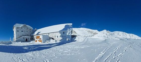 L’Ostello Campo Imperatore è una storica struttura situata nel cuore del massiccio del Gran Sasso, in Abruzzo. A oltre 2.100 metri di altitudine, offre un’accoglienza essenziale ma calorosa per escursionisti, alpinisti e amanti della montagna. La sua posizione strategica lo rende un punto di partenza ideale per esplorare le vette circostanti, tra cui il Corno Grande, la cima più alta dell’Appennino. Immerso in un paesaggio suggestivo, caratterizzato da ampie praterie d’alta quota e spettacolari vedute panoramiche, il rifugio rappresenta un luogo di sosta perfetto per chi cerca un contatto autentico con la natura. Le attività del rifugio variano a seconda delle stagioni, offrendo un’ampia gamma di esperienze per gli ospiti. Durante l’estate, è frequentato da escursionisti che percorrono i sentieri del Parco Nazionale del Gran Sasso e Monti della Laga, oltre che da appassionati di arrampicata e fotografi naturalisti. Nei mesi invernali, grazie alla sua vicinanza agli impianti sciistici di Campo Imperatore, diventa un punto di riferimento per sciatori, snowboarder e scialpinisti. La struttura offre anche spazi per incontri ed eventi, accogliendo gruppi organizzati e scuole di montagna interessate a esperienze educative e formative sull’ambiente alpino. L’ospitalità del rifugio è semplice e autentica, in linea con la tradizione delle strutture d’alta quota. Gli ospiti possono usufruire di camerate essenziali ma confortevoli, con un’atmosfera familiare che favorisce l’incontro tra viaggiatori con la stessa passione per la montagna. La ristorazione è improntata alla cucina tipica abruzzese, con piatti sostanziosi preparati con ingredienti locali, come zuppe calde, polenta e formaggi di montagna. Dopo una giornata trascorsa all’aria aperta, il rifugio diventa un luogo di convivialità, dove è possibile condividere racconti ed esperienze davanti a un camino acceso. Il Rifugio/Ostello Campo Imperatore conserva un fascino storico e culturale che lo rende unico. Oltre ad essere stato un punto di riferimento per esploratori e studiosi della montagna, ha anche un ruolo nella memoria collettiva italiana, avendo ospitato Mussolini durante la sua prigionia nel 1943 prima della celebre operazione di salvataggio. Questo passato si intreccia con la sua funzione attuale di accoglienza e scoperta, facendo di questa struttura un luogo che unisce storia, natura e avventura. Per chi desidera vivere la montagna nella sua essenza più pura, il rifugio rappresenta una destinazione imperdibile nel cuore dell’Abruzzo.