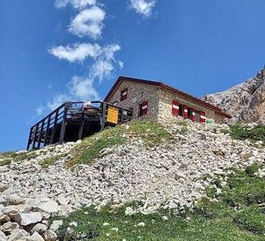 Il Rifugio Carlo Franchetti, situato a 2.433 metri di altitudine. Trekking in Abruzzo: l’Anello delle Fontari. Percorrere l’Anello delle Fontari significa immergersi in un ambiente montano di rara bellezza, dove il paesaggio cambia continuamente tra imponenti pareti rocciose, dolci pendii erbosi e panorami sconfinati. Situato nel cuore del Parco Nazionale del Gran Sasso e Monti della Laga, questo itinerario circolare permette di scoprire alcuni degli scorci più affascinanti della montagna abruzzese. Il silenzio avvolgente e l’aria limpida rendono ogni passo un’esperienza intensa, mentre la vista si apre su cime imponenti e valli selvagge che si perdono all’orizzonte. Il percorso, che si sviluppa tra creste panoramiche e sentieri ben segnalati, regala scorci spettacolari in ogni stagione. In primavera e in estate, i prati d’alta quota si tingono dei colori vivaci delle genziane e delle stelle alpine, mentre in autunno il paesaggio assume toni caldi e dorati. L’inverno, invece, trasforma il tracciato in un regno di neve e ghiaccio, offrendo un panorama di straordinaria purezza. Il cammino, tra tratti più dolci e salite più impegnative, si adatta agli escursionisti con una buona preparazione fisica e regala emozioni uniche a chi è alla ricerca di una connessione autentica con la natura. Uno dei punti più suggestivi del trekking è il Rifugio Carlo Franchetti, situato a oltre 2.400 metri di altitudine, incastonato tra le rocce e circondato da vette spettacolari. Qui è possibile concedersi una sosta rigenerante, ammirando il panorama mozzafiato e respirando l’aria pura dell’alta montagna. La vista spazia dalle creste frastagliate del Gran Sasso fino alle vallate sottostanti, regalando una sensazione di totale immersione nel cuore dell’Appennino. Il rifugio rappresenta un punto d’incontro per gli escursionisti e un luogo di ristoro ideale prima di proseguire lungo il sentiero. Lungo il percorso, la natura si manifesta in tutta la sua ricchezza e varietà. I più fortunati potranno avvistare il camoscio appenninico, elegante e agile abitante delle alte quote, o scorgere in cielo il volo maestoso dell’aquila reale, che domina questi territori con la sua presenza imponente. Tra le rocce, si possono incontrare piccole marmotte che si affacciano curiose dai loro rifugi, mentre il silenzio del paesaggio è interrotto solo dal sibilo del vento e dal rumore dell’acqua che scorre tra le pietre. Raggiungere il termine dell’Anello delle Fontari significa portare con sé il ricordo di un’esperienza autentica, fatta di fatica, bellezza e meraviglia. La luce che cambia nel corso della giornata dona al paesaggio sfumature sempre diverse, creando scenari unici che rimangono impressi nella memoria. Ogni passo su questo sentiero racconta la storia millenaria della montagna e lascia nell’animo un senso di gratitudine per aver camminato in uno degli angoli più spettacolari dell’Abruzzo.
