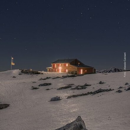 Il Rifugio Vincenzo Sebastiani, situato in Località Colletto di Pezza, nel comune di Rocca di Mezzo (AQ), è un punto di riferimento per gli escursionisti e gli amanti della montagna all'interno del Parco Naturale Regionale Sirente Velino. Immerso in un ambiente naturale straordinario, offre ospitalità e ristoro a chi desidera esplorare le bellezze delle montagne abruzzesi. La struttura, di proprietà del Club Alpino Italiano Sezione di Roma, è gestita con passione per garantire un'accoglienza autentica e familiare. Il rifugio rappresenta una base ideale per escursioni e trekking lungo i sentieri del Costone, con percorsi adatti a diverse difficoltà e livelli di esperienza. In inverno, la neve trasforma il paesaggio in un paradiso per gli appassionati di scialpinismo e ciaspolate. L'accesso al rifugio varia a seconda delle condizioni climatiche: con neve abbondante, il percorso più battuto parte da Campo Felice e richiede circa tre ore di cammino, mentre nei periodi con meno neve è possibile raggiungerlo partendo dalla miniera di Valle Leona o da Capo di Pezza in circa due ore. L'attività del rifugio si basa su un'accoglienza semplice e genuina, dove il calore umano e la condivisione sono elementi centrali. La struttura dispone di 25 posti letto e propone una cucina tipica di montagna, con piatti che esaltano i sapori locali e l'autenticità del territorio. L'atmosfera conviviale invita gli ospiti a rilassarsi dopo una giornata trascorsa all'aria aperta, creando un punto d'incontro tra escursionisti, alpinisti e appassionati di natura. Oltre all'ospitalità, il rifugio promuove iniziative ed eventi dedicati alla cultura della montagna, all'educazione ambientale e alla sicurezza in alta quota. La gestione, affidata a Eleonora Saggioro e alla Cooperativa Equo Rifugio, porta avanti con entusiasmo un progetto nato dalla passione per l'alpinismo e il desiderio di valorizzare questo luogo unico. Il rifugio rappresenta non solo un riparo per chi affronta la montagna, ma anche uno spazio di condivisione, scoperta e rispetto per la natura.