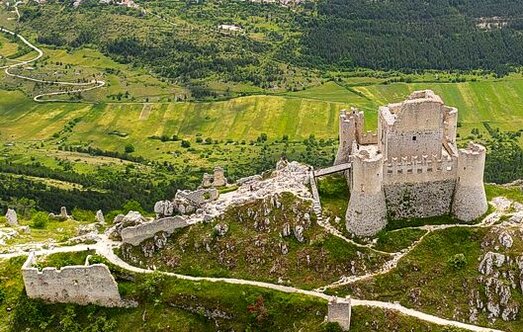 Il Castello di Rocca Calascio, il più scenografico dei castelli d’Abruzzo. Situato a 1460 metri di altitudine, il castello di Rocca Calascio è senza dubbio uno dei castelli più spettacolari e scenografici d’Abruzzo, un’autentica meraviglia che svetta come un nido d’aquila sopra l’altopiano di Campo Imperatore. La sua posizione dominante offre una vista mozzafiato su un paesaggio che spazia dalle vallate sottostanti fino alle vette dell'Appennino, rendendolo un punto di osservazione privilegiato e una delle fortezze più imponenti della regione. Il castello, costruito per controllare le antiche “vie della lana”, univa la funzione difensiva a quella di avvistamento, facendo da guardiano alle rotte commerciali che collegavano l’altopiano alle altre valli abruzzesi. Le origini della Rocca risalgono intorno all’anno Mille, quando fu eretto come un semplice torrione quadrangolare. Nel corso dei secoli, la struttura venne ampliata e rinforzata, divenendo un castello imponente, circondato da una robusta fortificazione con quattro torri cilindriche che gli conferirono il suo aspetto inconfondibile. Questo ampliamento, che ne aumentò la visibilità e l’efficacia difensiva, lo rese un simbolo di potere e sicurezza nella regione. La sua forma maestosa e la sua posizione strategica lo hanno reso uno dei castelli più fotografati e apprezzati d’Italia, tanto da essere diventato uno dei luoghi più iconici dell’Abruzzo. Nel corso dei secoli, la Rocca di Calascio cambiò molte volte di mano, passando da un gruppo di monaci benedettini, i Benedettini di San Vincenzo al Volturno, agli Acclozemora, e poi ai Piccolomini. Fu solo nel 1579 che il castello e la vicina Santo Stefano di Sessanio entrarono nei possedimenti dei Medici, che usarono la ricchezza derivante dal commercio della lana per ampliare e rafforzare la propria influenza nella regione. Durante questo periodo, la Rocca acquisì maggiore importanza come simbolo del potere dei Medici e come punto di controllo strategico. Oggi la Rocca di Calascio, pur trovandosi in stato di rovine, resta un simbolo potente del patrimonio storico e culturale dell’Abruzzo. Le sue rovine, immerse in un paesaggio spettacolare, continuano a raccontare la storia di un passato lontano, capace di affascinare i visitatori con la loro bellezza e il loro spirito indomito. Grazie alla sua magnificenza e alla posizione incantevole, la Rocca è diventata una meta privilegiata per chi desidera immergersi nella storia medievale e nella natura incontaminata dell’Abruzzo.