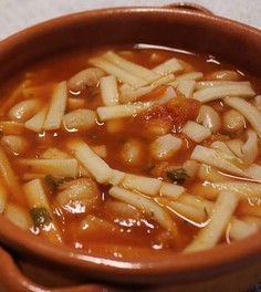 La preparazione delle sagne e fagioli, un piatto tipico della provincia di Chieti, è un rito che affonda le radici nella tradizione contadina, dove ogni gesto e ogni ingrediente raccontano una storia di semplicità e genuinità. Per realizzare questa pietanza, si inizia con la preparazione delle sagne, una pasta fatta a mano utilizzando farina di grano duro, acqua e un pizzico di sale. L’impasto, lavorato con cura fino a diventare liscio ed elastico, viene steso in una sfoglia sottile e poi tagliato in strisce corte e irregolari. Questa forma rustica conferisce al piatto una consistenza unica, capace di trattenere perfettamente il condimento. Parallelamente, si dedicano attenzione e tempo alla cottura dei fagioli, ingrediente fondamentale del piatto. Solitamente si utilizzano fagioli borlotti o cannellini, che vengono messi in ammollo per diverse ore, preferibilmente tutta la notte, per reidratarli e ammorbidirli. Successivamente, i fagioli vengono cotti a fuoco lento in acqua con l’aggiunta di una foglia di alloro, che dona al piatto un delicato profumo aromatico. Questa lenta cottura consente ai fagioli di sviluppare una consistenza cremosa e un sapore pieno, pronto per essere abbinato agli altri ingredienti. Il condimento viene preparato in una padella a parte, partendo da un soffritto semplice di aglio e olio extravergine d’oliva, simbolo dell’eccellenza abruzzese. A questo si aggiunge la passata di pomodoro, che con il suo sapore dolce e leggermente acidulo crea la base del sugo. Il peperoncino può essere aggiunto per chi desidera un tocco di vivacità, mentre il tutto viene lasciato cuocere lentamente per permettere ai sapori di amalgamarsi. Quando i fagioli sono pronti, vengono uniti al sugo, formando un condimento denso e profumato, che rappresenta il cuore del piatto. Infine, le sagne vengono cotte in acqua bollente salata fino a raggiungere una consistenza al dente. Una volta scolate, vengono mescolate con il condimento di fagioli e sugo, assicurandosi che ogni pezzo di pasta sia avvolto dal sapore intenso del condimento. Servito caldo, il piatto può essere arricchito con un filo di olio a crudo per esaltare i sapori o, per chi lo desidera, una leggera spolverata di pepe. Le sagne e fagioli, nella loro semplicità, celebrano la cucina tradizionale della provincia di Chieti, esprimendo il meglio dei sapori locali con autenticità e calore.