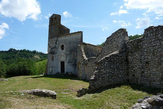 Isola del Gran Sasso (Te). Chiesa di San Giovanni ad Insulam. La chiesa di San Giovanni ad Insulam è stata costruita agli inizi del XII secolo e poi modificata alla fine del XIII secolo. Molto bello è il prospetto principale, uno dei primi esempi in Abruzzo di facciata a coronamento orizzontale, purtroppo alterata dall'aggiunta del campanile. La facciata è impreziosita dalla decorazione ad archetti pensili su mensole che prosegue sui fianchi e riprende lungo il semicerchi dell'abside. Il portale con archivolto inquadrato da un'edicola, ha stipiti decorati da eleganti figure in bassorilievo. L’interno è a tre navate e ha colonne con capitelli di diversa forma; il presbiterio è sopraelevato per lasciare spazio alla sottostante cripta. Interessante il frammentario affresco di San Giovanni Battista situato sulla calotta absidale e datato 1421. La cripta è divisa in tre navatelle, ha volte a crociera sostenute da colonne circolari e presenta una piccola abside. La chiesa di San Giovanni ad Insulam, detta anche chiesa di San Giovanni al Mavone, sorge isolata sopra un piccolo poggio che fiancheggia il fiume Mavone nell'omonima valle. Si trova nei pressi del paese di Isola del Gran Sasso, nel territorio della provincia di Teramo in Abruzzo, immersa nella catena appenninica alle falde del Gran Sasso le cui cime del Corno Grande e del Corno Piccolo da una parte, e i monti Prena e Camicia dall'altra ne incorniciano il panorama. Il prospetto frontale della Chiesa di San Giovanni ad Insulam a Isola del Gran Sasso è aperto da un ricco portale rialzato da alcuni gradini, un oculo e da due bifore di gusto pugliese, rare a trovarsi negli edifici abruzzesi. Queste sono incorniciate da una ghiera a tutto sesto, che si mostra liscia a spigolo vivo, e ricavate nello stretto spazio di un archetto ad ogiva, ripartite nelle due luci da una colonnina che presenta la base ed il capitello di uguale dimensione delle fessure. Si evidenzia, sopra il timpano del portale, l'oculo, considerato dal Moretti una possibile aggiunta postuma alla realizzazione originaria e del quale si pensa possa essere andata perduta la lavorazione a traforo. La caratteristica di questa facciata a terminazione piana, che Gavini ritiene adottata per la prima volta in Abruzzo nella costruzione di questo complesso monumentale, fu utilizzata come prototipo architettonico per lo stile di altri edifici abruzzesi del XIV e XV secolo, sorti soprattutto nel territorio aquilano. I fianchi della Chiesa di San Giovanni ad Insulam a Isola del Gran Sasso: I fianchi della costruzione sono aperti da piccole finestre a feritoia sopra le quali si nota la stratigrafia dell'alternanza di fasce di pietre e laterizi rossi, dovuta ad interventi di sopraelevazione della fabbrica, seguita da un secondo ordine di monofore. La cornice di coronamento è definita a «spinapesce» ed archetti. Il prospetto posteriore è movimentato dalla sporgenza dell'abside elevata in due tempi. I portali della Chiesa di San Giovanni ad Insulam a Isola del Gran Sasso. Il portale principale: Spicca per originalità nel suo schema compositivo e si mostra riccamente intessuto di decori proponendo un diverso e nuovo impianto architettonico. Databile nella prima metà del XII secolo, si apre in uno spazio rettangolare sovrastato dalla lunetta racchiusa all'interno di un'edicola. I decori in bassorilievo dell'archivolto sono scalpellati con motivi di girali d'acanto riferibili ai modelli classici riproposti anche nel più elaborato architrave ed affini a quelli della chiesa di San Clemente al Vomano. Gli stipiti non sono costituiti da pilastri, ma si compongono di conci di pietra squadrati e sovrapposti che mostrano bassorilievi di figure zoomorfe e mostruose di gusto liberatoriano.