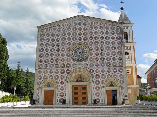 Il Santuario del Volto Santo a Manoppello (Pe) Il culto del Volto Santo di Manoppello affonda le sue radici nel profondo legame spirituale che i fedeli nutrono nei confronti di una reliquia che ha suscitato da secoli un grande fervore devozionale. La reliquia, che consiste in un velo che conserva l'immagine del volto di Cristo, è considerata miracolosa per la sua straordinaria bellezza e per la sua apparente indistruttibilità. Secondo la tradizione, il Volto Santo è arrivato a Manoppello in tempi antichi e ha attirato numerosi pellegrini, che vengono a venerarlo in quanto simbolo della passione, morte e resurrezione di Cristo. L'immagine, che sembra quasi viva, è custodita all'interno del santuario, dove ogni anno migliaia di persone si riuniscono per pregare e riflettere sul mistero della fede cristiana. La devozione al Volto Santo si è consolidata nel corso dei secoli grazie anche alla sua straordinaria capacità di attrarre l'attenzione per la sua naturalezza e per la sua capacità di generare un forte impatto emotivo sui credenti. Il culto si è diffuso non solo a livello locale, ma anche tra i pellegrini che provengono da diverse parti d'Italia e del mondo. Ogni anno, infatti, il Santuario del Volto Santo di Manoppello ospita numerose celebrazioni liturgiche, durante le quali la reliquia viene esposta ai fedeli. Questi momenti di preghiera collettiva sono accompagnati da canti, letture e meditazioni che rievocano il significato del Volto Santo come simbolo della presenza di Cristo nella vita quotidiana dei credenti. Nel corso del tempo, il culto del Volto Santo ha avuto anche una grande importanza per la vita religiosa di Manoppello e dei suoi abitanti. La chiesa che ospita la reliquia è diventata il cuore pulsante della comunità, dove ogni domenica e durante le festività principali, i fedeli si riuniscono per celebrare la liturgia. L'importanza del culto si riflette anche nelle numerose opere di carità e nei progetti sociali che sono stati avviati nel nome del Volto Santo, contribuendo a rafforzare il senso di comunità e solidarietà tra i cittadini. Questo culto non è solo un atto di devozione, ma anche una testimonianza di come la fede possa unire le persone in un comune cammino spirituale. Il culto del Volto Santo di Manoppello è oggi un simbolo di speranza e di spiritualità per tutti coloro che cercano nella figura di Cristo un rifugio dalla sofferenza e una guida nella vita. La reliquia non solo alimenta la fede, ma diventa anche un punto di riferimento per chi si sente lontano da Dio e desidera riconciliarsi con Lui. Ogni anno, durante le festività, il Santuario diventa un luogo di pellegrinaggio, dove i fedeli si riuniscono per rinnovare il loro impegno religioso e per chiedere grazie e benedizioni. Il culto del Volto Santo di Manoppello continua a vivere nel cuore dei credenti, mantenendo viva la tradizione di fede e di amore che si è tramandata nel corso dei secoli. Manoppello (Pe) Santuario del Volto Santo. Manoppello merita una visita per la straordinaria bellezza di due complessi religiosi di grande valore storico-artistico: l'Abbazia di Santa Maria Arabona, posta su una collinetta e circondata dal verde dei pini, e il Convento Santuario del Volto Santo. Complessa è la storia dell'Abbazia: fondata nel 1208 vicino a un preesistente monastero dei Frati Benedettini, venne soppressa come struttura religiosa ai tempi del dominio di Napoleone. A quel punto, i baroni Zambra di Chieti la riscattarono e trasformarono tutta la parte anticamente occupata dalle celle dei monaci nella loro residenza di campagna. E come villa privata rimase sino al 1977, quando l'ultima baronessa Zambra decise di farne donazione all'ordine dei Salesiani, che hanno provveduto a una massiccia opera di restauro valorizzando le antiche strutture originarie. Diverse le vicende che hanno invece contraddistinto la storia del Convento Santuario del Volto Santo dei Frati Francescani Cappuccini. Le sue sembianze moderne non devono trarre in inganno: la chiesa fu fondata dai Frati Minori Cappuccini tra il 1617 e il 1638, è stata più volte sottoposta a interventi di restauro e, al suo interno, sono conservate pregiate tele del Seicento oltre che la preziosa teca con il Volto Santo. Tradizione vuole che, nel lontano 1506, un misterioso pellegrino sia giunto sino a Manoppello e, prima di svanire di nuovo in quel nulla da cui era venuto, abbia consegnato a Giacomantonio Leonelli l'antico velo che la Veronica porse a Gesù sulla via del Calvario e sul quale restò impresso il volto sofferente di Cristo. Leggende a parte, stando ad alcuni studiosi il velo del Volto Santo sarebbe lo stesso che Dante citò nella Divina Commedia e che sparì dalla romana Basilica di San Pietro 400 anni fa. In ogni caso, il Volto Santo venne riposto in una teca di vetro e donato al convento nel 1638, dove rimase fino al 1686, quando venne trasferito nella Chiesa di San Michele Arcangelo, primo nucleo di quello che è l'attuale Santuario, oggi elevato all'onore di Basilica Minore.