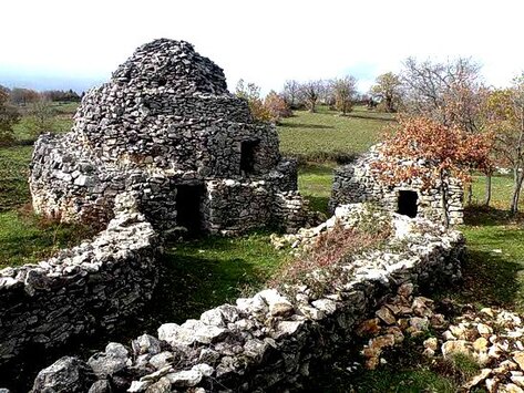 Sito Archeologico dei Tholos della Majella a Roccamorice (PE). Il sito archeologico dei Tholos della Majella a Roccamorice rappresenta una testimonianza unica dell'ingegno e della tradizione pastorale abruzzese. Queste costruzioni in pietra, conosciute localmente come "pajare", sono il frutto del lavoro secolare di pastori e contadini che hanno modellato il paesaggio montano per ricavare spazi di rifugio e di lavoro. La tecnica utilizzata per la loro realizzazione, basata sulla costruzione a secco, prevede la sovrapposizione concentrica di pietre senza l'utilizzo di leganti, creando strutture dalla sorprendente solidità e durata nel tempo. Gli ingressi delle capanne sono frutto di soluzioni architettoniche ingegnose, che vanno da semplici architravi orizzontali in pietra a sistemi più complessi con archi e triangoli di scarico. Questa varietà di soluzioni riflette l'abilità costruttiva e l'adattamento alle diverse esigenze funzionali. La catalogazione realizzata dallo studioso Edoardo Micati ha permesso di classificare e tutelare le capanne a tholos della Majella, riconosciute come patrimonio architettonico grazie a una legge regionale che ne garantisce la conservazione. Le capanne, costruite in epoche remote e utilizzate fino alla metà del Novecento, erano principalmente destinate a ricoveri per pastori, stalle, fienili o depositi di attrezzi agricoli. Ancora oggi, alcune strutture vengono utilizzate dai pastori durante la stagione estiva, testimoniando un legame ininterrotto con la tradizione e con l'ambiente montano. La loro presenza racconta la storia di una comunità capace di adattarsi alle difficili condizioni naturali, trasformando la pietra in una risorsa indispensabile per la vita quotidiana. Grazie a interventi di restauro e valorizzazione, molte capanne a tholos sono state recuperate e rese accessibili al pubblico. Escursioni e percorsi guidati permettono di ammirare questi straordinari esempi di architettura rurale in luoghi come le Case Pagliari, il Fosso Capanna e la Majelletta a Roccamorice, Decontra a Caramanico e la Valle Giumentina ad Abbateggio. La strada panoramica che da Roccamorice conduce alla Majelletta offre una visione suggestiva di questo patrimonio, permettendo di apprezzarne la bellezza e la rilevanza storica.