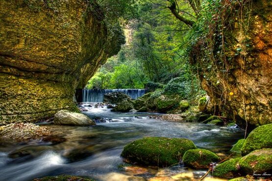 Trekking nelle valli dell’Abruzzo: La valle dell’Orfento. Trekking nelle valli dell’Abruzzo: La valle dell’Orfento. La Valle dell’Orfento, situata nel Parco Nazionale della Majella, è uno dei luoghi più selvaggi e suggestivi dell’Abruzzo. Il vallone si estende dalla cima del Focalone, a 2676 metri, fino ai 556 metri di altitudine di Caramanico Terme. Questa lunga discesa attraversa un paesaggio incantevole, dove la natura ha mantenuto intatta la sua forza selvaggia. Caramanico, famosa per le sue terme e le chiese medievali, costituisce il punto di partenza ideale per esplorare la valle. Il percorso che segue il fiume Orfento permette di ammirare scenari rocciosi straordinari e offre l’opportunità di scoprire luoghi storici come l’eremo di Sant’Onofrio e il ponte medievale di San Cataldo. L'accesso all'Orfento è regolato per garantire la protezione di quest’area naturale incontaminata, richiedendo ai visitatori di ritirare un permesso gratuito presso il Centro Visite di Caramanico. La camminata lungo il fiume Orfento è un'esperienza che porta a scoprire un mondo fatto di silenzi interrotti dal rumore dell’acqua e dalle meraviglie naturali che circondano il sentiero. Lungo il percorso, il fiume si fa strada tra le rocce, formando piccole cascate e marmitte, e la vegetazione diventa sempre più fitta man mano che si procede, nascondendo il cielo sopra di noi. Nel cuore della valle, la sensazione di essere immersi in un paesaggio primitivo cresce. La vegetazione lussureggiante e le pareti di roccia che sovrastano il sentiero creano un’atmosfera magica, in cui è facile sentirsi parte di un mondo remoto e incontaminato. Le passerelle in legno permettono di attraversare il fiume più volte, rendendo il cammino accessibile e sicuro, ma senza compromettere il fascino selvaggio del luogo. Ogni angolo della valle racconta una storia di erosione e crescita, testimoniata dalle formazioni rocciose scolpite dall'acqua in migliaia di anni. Il percorso culmina nei pressi del Ponte di Caramanico, un'antica struttura che si staglia tra le rocce e la vegetazione. Questo ponte rappresenta un punto di arrivo ideale per chi vuole ammirare la maestosità della valle dall'alto. Qui, la vista è impareggiabile e offre un’occasione unica per osservare la fauna locale, come i balestrucci che nidificano sotto il ponte. La camminata, pur impegnativa, è una delle esperienze più affascinanti che la Valle dell’Orfento ha da offrire, e chiunque la percorra sarà ricompensato da uno dei paesaggi più intatti e emozionanti dell’Abruzzo.