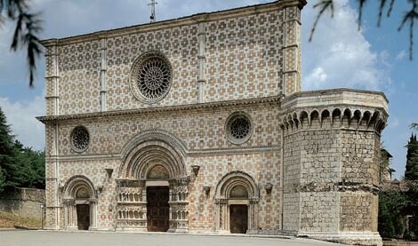 L’Abruzzo fu fra le prime regioni italiane a vivere l’impatto vivificante della cristianizzazione, e subito dopo quello rivoluzionario del monachesimo benedettino. Si può anzi dire che, nel quadro severo delle sue montagne e delle difficili condizioni di vita che esse imponevano, è stato essenzialmente il cristianesimo a modellare il profilo culturale e spirituale dell’Abruzzo. La decisiva prevalenza che dal Medioevo questa cultura ebbe rispetto a quella laica e civile nel delineare l’identità regionale, non dipese soltanto dalla forte e primitiva Natura dell’Abruzzo (che ha da sempre costretto i suoi abitanti a confrontarsi col mistero della trascendenza) ma anche e soprattutto dalla mancanza di importanti corti signorili nella regione, e dalla marginalità politica che il territorio assunse rispetto ai centri di potere del Regno di Napoli. I feudatari che si avvicendavano nei suoi castelli, quasi sempre forestieri e spesso neanche residenti, ebbero una limitata incidenza sulla vita civile della regione; non furono pertanto nelle loro dimore, ma nei conventi e nelle abbazie i centri propulsori effettivi della storia abruzzese. Per questa ragione, l’architettura religiosa ha espresso in Abruzzo una prevalenza nettissima su quella civile: una prevalenza che è innanzitutto quantitativa, giacché il numero di edifici religiosi di ogni tipo, urbani e rurali, è enorme e imparagonabile agli edifici civili (soprattutto urbani); ma anche qualitativa, perché fu di nuovo il cristianesimo a introdurre e sviluppare con originalità del tutto locale i nuovi linguaggi e le nuove esperienze dell’architettura europea. “Dal convento di San Liberatore della Majella, fin dagli anni fra il 1007 e il 1019, uscirono alcune maestranze di benedettini che diffusero nella contrada un tipo di architettura in cui si ritrovavano fusi con semplicità e originalità elementi latini e lombardi; i monaci valvensi nel XII secolo propagarono l’architettura romanica; i cistercensi, venuti di Francia, introdussero più tardi le forme gotiche di Borgogna; finché nel XIII secolo fiorirono numerose scuole locali, in gara artistica tra di loro, per opera delle fraterie di Atri, Teramo, Chieti, L’Aquila, Sulmona, Lanciano e della Marsica, che pur nella ricchezza e diversità o eclettismo di stile e nella mancanza di eccezionali individualità, ci rivelano ancor oggi un gusto comune assai elevato, un evidente amore per la sobrietà, la chiarezza, la forza.” (Ignazio Silone). Questo primato si è concretizzato in un gran numero di monumenti religiosi di importanza e bellezza assoluti, spesso noti anche a livello internazionale, diffusamente distribuiti sia nei maggiori centri abitati sia nei borghi più piccoli e sperduti, quando non isolati e incastonati nel paesaggio come veri gioielli dello spirito. Questi monumenti hanno aspetti e caratteri diversi: possono essere orgogliose cattedrali urbane integrate nei centri storici maggiori o piccole pievi di paese, solitarie chiese tratturali o campestri armonicamente inserite nel paesaggio, ascetici oratori montani o severi monasteri fortificati. Ma ognuno di essi è uno scrigno di spiritualità e di tesori d'arte. Un patrimonio che originò soprattutto nel Medioevo, sostenuto dalle crescenti ricchezze che la chiesa e la borghesia locali poterono impegnare grazie alla più importante attività produttiva della regione: la Pastorizia.