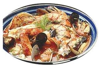 Il Brodetto tradizionale alla giuliese è un piatto che rappresenta la ricchezza del mare Adriatico, caratteristico della provincia di Teramo. La sua preparazione varia in base al mercato, poiché non esistono varietà o quantità fisse di pesce. Tuttavia, i pesci utilizzati, come la gallinella, la razza, lo scorfano, il palombo, la triglia, la rana pescatrice, la seppia, la canocchia, la sogliola, lo scampo, le vongole e la tracina, contribuiscono a creare un piatto ricco di sapori di mare. La versatilità dei pesci, combinata con i frutti di mare, conferisce al brodetto una profondità di gusto unica, che varia a seconda degli ingredienti disponibili. Il brodetto si prepara partendo da un soffritto delicato di aglio tritato e olio extra vergine di oliva, cui si aggiungono pomodoro maturo, sale e un pizzico di peperoncino, che arricchiscono il sapore con una leggera nota piccante. Il pomodoro, essendo fresco e maturo, fornisce una base acidula e dolce, che si fonde perfettamente con i sapori intensi del pesce e dei frutti di mare. La combinazione di questi ingredienti crea un brodetto dal profumo avvolgente e dal colore rosato, che anticipa il gusto ricco e corposo del piatto. Nella preparazione, i pesci più coriacei, come scorfano, gallinella e palombo, vengono aggiunti prima, poiché richiedono un tempo di cottura maggiore. Successivamente, si aggiungono quelli con carne più tenera, come la sogliola e lo scampo, e infine i frutti di mare come le vongole. Ogni ingrediente contribuisce con il proprio sapore unico: il pesce bianco dona delicatezza, mentre i frutti di mare apportano una nota salina e umami, rendendo il brodetto estremamente saporito e armonioso. Per completare il piatto, si aggiunge pane tostato, che assorbe il sugo ricco e aromatizzato, e un tocco finale di prezzemolo fresco tritato, che dona freschezza e colore al piatto. Il brodetto viene servito direttamente dal tegame, mantenendo la sua temperatura ideale. Per accompagnarlo, si consiglia un vino bianco come il Montepulciano d'Abruzzo Cerasuolo, che con la sua freschezza e acidità bilancia perfettamente la ricchezza del brodetto, creando un equilibrio di sapori che esalta ogni ingrediente.