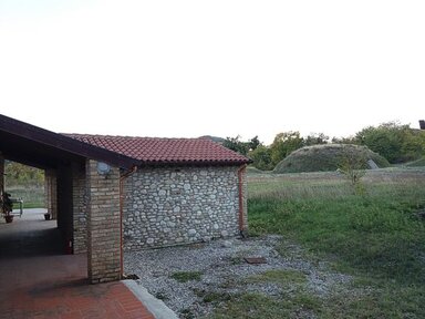 La necropoli di Campovalano - Campli (Te) La necropoli di Campovalano, situata nel territorio di Campli, nella provincia di Teramo, rappresenta uno dei più importanti siti archeologici dell’Abruzzo e una delle testimonianze più significative della cultura italica nell’Italia centrale. Questo luogo sacro, utilizzato come area funeraria per un lungo arco di tempo, rivela molto delle popolazioni che abitarono l'area tra l’età del Bronzo e l’epoca romana. Gli scavi hanno portato alla luce numerose tombe, risalenti soprattutto al periodo compreso tra l’VIII e il III secolo a.C., che attestano l’evoluzione delle pratiche funerarie nel corso dei secoli. Le tombe, di diverse dimensioni e tipologie, erano generalmente accompagnate da ricchi corredi funerari, composti da ceramiche, gioielli, armi e utensili di uso quotidiano. Questi reperti riflettono non solo le abitudini e le credenze religiose delle comunità antiche, ma anche le stratificazioni sociali presenti all’interno di quelle società. Le tombe principesche, in particolare, offrono una visione affascinante del prestigio e della ricchezza di alcune famiglie, con corredi contenenti oggetti di lusso, spesso importati da altre regioni, a dimostrazione della vivacità dei commerci e dei contatti culturali. Le ceramiche e i bronzi ritrovati mostrano influenze etrusche e greche, evidenziando la centralità di Campovalano nelle reti di scambio dell'epoca. La necropoli è stata valorizzata attraverso attività di ricerca, scavi archeologici e la creazione di un allestimento museale che ne narra la storia. Molti dei reperti ritrovati sono oggi esposti nel Museo Archeologico Nazionale di Campli, dove i visitatori possono ammirare da vicino i manufatti e approfondire le conoscenze sulla vita e le tradizioni delle antiche popolazioni italiche. Inserita in uno scenario naturale di rara bellezza, la necropoli di Campovalano non è solo un sito archeologico di rilievo, ma anche un luogo di memoria che racconta le origini storiche e culturali del territorio teramano. Questo complesso funebre offre una finestra sul passato, evidenziando il profondo legame tra vita, morte e il paesaggio circostante.