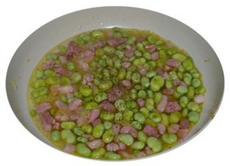 Le Fave con pancetta è un piatto tradizionale che esprime perfettamente la cucina rustica e genuina della provincia di Pescara, mettendo in risalto alcuni dei prodotti tipici più rappresentativi dell'Abruzzo. Per prima cosa, le fave, simbolo della tradizione contadina, vengono cotte lentamente fino a diventare morbide e cremose. Le fave secche, che in Abruzzo sono coltivate in diverse varianti, hanno un sapore delicato che, una volta cotte, si amalgama bene con i condimenti e diventa il perfetto accompagnamento per gli altri ingredienti. La pancetta, un altro elemento fondamentale della cucina abruzzese, contribuisce con la sua ricchezza e sapidità. La pancetta abruzzese è nota per la sua qualità e per il processo di salatura che la rende un ingrediente versatile, utilizzato in numerose ricette tradizionali. Quando rosolata, la pancetta sprigiona un aroma avvolgente e si trasforma in una croccante prelibatezza che, insieme alla dolcezza delle fave, crea un equilibrio di sapori molto apprezzato. Un altro ingrediente imprescindibile della preparazione è l'olio extravergine d'oliva, prodotto di punta della regione. L'olio abruzzese, noto per il suo sapore fruttato e leggermente piccante, è perfetto per il soffritto, che costituisce la base del piatto. Cipolla e aglio, che fanno parte della cucina tradizionale abruzzese, vengono soffritti insieme all'olio per creare una base saporita che arricchisce il piatto, mentre l'olio contribuisce a esaltare i sapori e a legare gli ingredienti in un’unica preparazione armoniosa. Infine, per dare il tocco finale al piatto, le fave e la pancetta vengono mescolate insieme, permettendo ai sapori di amalgamarsi e diventare un tutt'uno. Il piatto, ricco di sapori e di tradizione, rispecchia il cuore della cucina abruzzese: pochi ingredienti locali ma di qualità, che, nella loro semplicità, danno vita a un piatto che sa di casa, di terra e di mare. Servito con del pane casereccio, è il piatto perfetto per godersi i sapori autentici dell’Abruzzo.