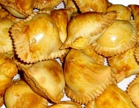 La preparazione dei Fiadoni è un viaggio nei sapori autentici della provincia di Pescara, dove i prodotti tipici abruzzesi si combinano per creare un piatto semplice ma ricco di carattere. La pasta, base di questa ricetta, si realizza con farina e uova fresche, provenienti da allevamenti locali, insieme a olio extravergine d’oliva, elemento essenziale della cucina abruzzese. Questo olio, ottenuto da cultivar autoctone come la Dritta, conferisce alla pasta una morbidezza e un sapore unici, che la rendono perfetta per accogliere il ripieno. Il ripieno dei Fiadoni è una celebrazione dei formaggi tipici del territorio. Il pecorino abruzzese, stagionato e dal sapore intenso, è il protagonista indiscusso, accompagnato spesso dal rigatino fresco, un formaggio più delicato ma altrettanto saporito. Questi formaggi vengono grattugiati e amalgamati con uova, che donano una consistenza cremosa e permettono al ripieno di rimanere compatto durante la cottura. Un pizzico di noce moscata, spezia aromatica dal profumo inconfondibile, completa il ripieno, aggiungendo una nota calda e avvolgente. Una volta preparati pasta e ripieno, si passa alla lavorazione dei Fiadoni. La pasta viene stesa in una sfoglia sottile, quindi ritagliata in quadrati o cerchi, pronti per essere farciti. Al centro di ogni pezzo si dispone una generosa quantità di ripieno, e i bordi vengono sigillati accuratamente, spesso creando la forma a mezzaluna tipica di questa ricetta. Un’incisione sulla parte superiore permette al ripieno di espandersi leggermente durante la cottura, garantendo una consistenza perfetta e un aspetto invitante. La cottura in forno trasforma i Fiadoni in piccoli capolavori dorati. La pasta assume una consistenza fragrante, mentre il ripieno sprigiona un aroma irresistibile grazie alla fusione dei formaggi e delle uova. Il risultato finale è un prodotto che esprime tutta la ricchezza della tradizione culinaria abruzzese. Serviti caldi o a temperatura ambiente, i Fiadoni sono un simbolo della cucina pescarese, in cui i sapori locali e le tecniche tradizionali si uniscono per creare un’esperienza gastronomica indimenticabile.