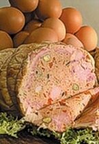 La galantina è uno dei piatti simbolo della cucina tradizionale teramana, un autentico capolavoro di sapori e maestria culinaria che porta con sé la storia e le tradizioni della terra d’Abruzzo. Preparata con il pollo, sapientemente disossato e farcito, questa pietanza rappresenta l’arte del trasformare ingredienti semplici in un cibo raffinato e ricco di gusto. Il ripieno, composto da carne macinata, prosciutto, olive, uova sode e spezie come la noce moscata, viene avvolto nella pelle del pollo e cotto lentamente in un brodo aromatico. Il risultato finale è un piatto che unisce morbidezza, intensità e profumi che richiamano la genuinità dei prodotti locali. Questa specialità, tradizionalmente servita fredda, era il cibo delle grandi occasioni, quando le famiglie si riunivano per celebrare feste e ricorrenze. La galantina, con il suo aspetto elegante e i sapori ben equilibrati, era una presenza immancabile nelle tavole teramane, capace di soddisfare i palati con la sua ricchezza senza mai risultare eccessiva. Oltre alla bontà, questo piatto conserva un legame profondo con il territorio, grazie all’utilizzo di ingredienti genuini come le verdure fresche del brodo e il pollo allevato nelle campagne locali, simboli della tradizione contadina. Ciò che rende unica la galantina è l’armonia tra i suoi sapori e la cura necessaria per la sua preparazione. Ogni passaggio, dal disossare il pollo al cucire la pelle che racchiude il ripieno, richiede precisione e dedizione, rendendo questo piatto non solo una ricetta, ma un rito che parla di tradizioni tramandate di generazione in generazione. La cottura lenta nel brodo arricchito con carote, sedano e cipolle esalta ogni elemento del piatto, donando al ripieno una consistenza compatta e un sapore che racchiude tutta l’essenza della cucina abruzzese. Oggi, la galantina continua a essere un simbolo della gastronomia teramana, apprezzata non solo nelle occasioni speciali, ma anche come testimonianza di una cucina che celebra la memoria e la creatività. Ogni fetta racconta storie di famiglie, di mani esperte e di ricette custodite con amore. Assaggiarla significa fare un viaggio nei sapori autentici di Teramo, dove tradizione e passione si incontrano per creare un’esperienza culinaria unica e indimenticabile.