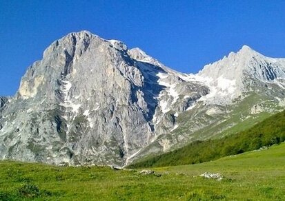I monti d’Abruzzo La regione è innanzitutto terra di montagne. Basta alzare lo sguardo verso l'interno da un punto qualsiasi della costa per incontrare la teoria ininterrotta di cime rocciose che si alzano verso il cielo: da nord verso sud sono i massicci della Laga, del Gran Sasso e della Majella. Un fantastico mondo di alta quota che rappresenta la spina dorsale di roccia di questa regione e costituisce il più formidabile complesso montano dell’Appennino (con caratteristiche francamente alpine), nel cuore dell’Italia e del Mediterraneo. Vi si trovano vette aguzze che sfiorano i 3000 metri, immensi pianori intramontani, strette gole scavate da torrenti impetuosi e ampie valli erose da antichi ghiacciai, laghi e cascate, forre selvagge e ampi pascoli, boschi infiniti, mughete e steppe d’alta quota. E tutto questo profuma di mare, giacché l'Adriatico dista solo qualche decina di chilometri. In mezzo ci sono solo dolci colline custodi di ulivi e vigne, ricche di tradizioni e sapori. Fra gli ambienti montani abruzzesi l’attrattiva più spettacolare sono in assoluto i grandi altipiani: nessuno si aspetta di trovare il Tibet a un’ora di macchina da Roma. Si tratta di ampie pianure intramontane, alcune larghe solo qualche chilometro, ma altre anche decine e decine, formatesi durante le ere geologiche per l'azione dei ghiacciai, ma anche per via della natura fortemente carsica dei monti. La prima visita a uno dei grandi altopiani d'Abruzzo, soprattutto se parliamo di Campo Imperatore (che è il più spettacolare, con i suoi spazi enormi e sorprendentemente simili al Tibet) è un’esperienza affascinante, capace di restare nella memoria per tutta la vita. Oltre al Campo Imperatore ricordiamo il Piano di Cascina, a nord dell'Aquila verso i confini con il Lazio, il Voltigno, che dai crinali del Gran Sasso si affaccia verso la provincia di Pescara, gli Altopiani delle Rocche, incuneati tra le vette del Sirente e del Velino, con i vicini Piani di Pezza e i Prati del Sirente, i piani di Passo San Leonardo sulla Majella, per chiudere nell’area montana meridionale con l’altro enorme e articolato complesso degli Altipiani Maggiori d’Abruzzo: il Piano delle Cinquemiglia, quello dell’Aremogna (sopra Roccaraso), i piani fra Roccaraso, Rivisondoli, Pescocostanzo, il bosco di Sant’Antonio e il valico della Forchetta. Ci sono poi degli ambienti pianeggianti tra le vette, detti dai geologi e dai geografi “pianori sommitali d’alta quota”, che riservano sorprese altrettanto emozionanti, per quel loro ambiente lunare, estremo: parliamo del Vallone di Femmina Morta, sulla Majella, o della Serra di Chiarano, a cerniera fra i monti del Parco Nazionale d’Abruzzo Lazio e Molise e la Majella; luoghi un po’ più difficili da raggiungere ma che offrono una esperienza ambientale unica.