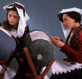 La tessitura e il merletto sono due delle più raffinate espressioni dell’artigianato tradizionale abruzzese, dove la cura dei dettagli diventa l’essenza stessa della creazione. Nelle valli e nei borghi dell’entroterra, il mestiere della tessitrice e della merlettaia ha radici profonde che affondano nella cultura popolare e nella vita quotidiana delle comunità. Ogni pezzo realizzato non è solo un oggetto, ma una storia raccontata attraverso fili e trame, una memoria che si tramanda da generazione in generazione. A Taranta Peligna, nel cuore dell’Abruzzo, la tessitura è un’arte che affonda le sue radici nei telai tradizionali utilizzati per creare arazzi, coperte e scialli. Ogni tessuto è il risultato di un processo lungo e meticoloso, dove ogni passaggio è eseguito con grande attenzione e dedizione. I motivi geometrici e i colori naturali che caratterizzano questi tessuti riflettono la bellezza del paesaggio circostante e l’esperienza di chi ha perfezionato questa arte nel tempo, con la pazienza che solo l’artigianato più autentico sa richiedere. L’arte del merletto a tombolo, che trova il suo apice a Pescocostanzo, è un altro esempio di come la lavorazione dei fili possa trasformarsi in un gesto artistico. Qui le merlettaie, con mani esperte, intrecciano fili sottilissimi su fuselli, creando disegni delicati e complessi che decorano tovaglie, centrini e inserti per abiti. Ogni punto, ogni intreccio, ogni curva è il frutto di un’abilità straordinaria, dove la tecnica si mescola con la passione, dando vita a merletti che sono veri capolavori di finezza e bellezza. La cura dei dettagli nell’artigianato tradizionale abruzzese non è solo una questione estetica, ma un vero e proprio linguaggio che parla di tradizione, cultura e identità. Ogni tessuto, ogni merletto realizzato è un piccolo frammento di storia, una testimonianza tangibile di un sapere antico che ancora oggi resiste al passare del tempo. In queste creazioni non c’è solo il lavoro dell’artigiano, ma l’anima di un territorio che, attraverso la sua arte, racconta chi è e da dove viene.