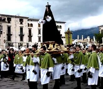 La "Madonna che scappa" di Sulmona è una delle tradizioni pasquali più suggestive e simboliche dell'Abruzzo, un evento che cattura l'attenzione e il cuore di chiunque vi partecipi. Ogni anno, durante la Domenica di Pasqua, la città si trasforma in un palcoscenico vivente per un rito che affonda le radici nella storia medievale e che coinvolge tutta la comunità. Il momento clou della festa è l’incontro tra la Madonna e il Cristo risorto, un avvenimento carico di emozioni che lascia senza fiato tutti i presenti. La tradizione della "Madonna che scappa" rappresenta simbolicamente la gioia della Resurrezione e la fine del dolore, celebrando la vittoria della vita sulla morte. L'origine di questa manifestazione affonda le sue radici nel XVI e XVII secolo, ma è nel XIX secolo che la festa assume la forma che conosciamo oggi. La storia racconta che la Madonna, appena ha notizia della resurrezione del Figlio, esce dalla chiesa di San Filippo, avvolta nel lutto e nella tristezza, simbolo del dolore materno. La Confraternita di San Giovanni, che si fa portavoce di questa notizia, annuncia il miracolo, ma non sarà facile per la Madonna accogliere la verità. Inizialmente, il portone della chiesa rimane chiuso, fino a quando Giovanni e poi Pietro non riescono a convincerla a uscire. Questo passaggio segna l'inizio del rito e la preparazione del pubblico all'emozionante scena che si svolgerà successivamente. Quando la statua della Madonna esce, vestita di nero, inizia una lenta marcia verso il centro della piazza, preceduta dal suono dei tamburi e dall’attesa palpabile della folla. La sua figura, immobile e incredula, si avvia alla ricerca del Figlio risorto, che appare sotto l'arcata dell'Acquedotto Svevo. È in questo momento che la Madonna inizia a "scappare", correndo con il cuore colmo di speranza e gioia. Questo gesto rappresenta simbolicamente la trasformazione del lutto in vita, il passaggio dalla sofferenza alla liberazione. La corsa, veloce e improvvisa, è accompagnata da un segno miracoloso: il manto nero della Madonna si trasforma in verde, un simbolo di speranza e rinascita. La trasformazione del manto, che avviene grazie a un meccanismo nascosto nella statua, è uno degli aspetti più significativi del rito. Se il meccanismo funziona correttamente e la Madonna scappa senza intoppi, la comunità considera l’anno come favorevole. Tuttavia, se qualcosa va storto, come il fallimento del meccanismo o l'inciampo di chi porta la statua, questo viene interpretato come un segno negativo. La festa, dunque, non è solo un evento folkloristico, ma anche un momento di riflessione e di speranza collettiva, dove la comunità si raccoglie per celebrare la Resurrezione e augurarsi un futuro prospero. La "Madonna che scappa" è un esempio di come la tradizione religiosa si intrecci con il folklore popolare, creando un’esperienza unica che coinvolge profondamente la città di Sulmona e chiunque vi assista. La festa non è solo una celebrazione della Pasqua, ma una manifestazione di fede che unisce generazioni e persone di ogni estrazione sociale. Ogni anno, la città si riempie di turisti e fedeli, tutti partecipi di una tradizione che, sebbene risalga a secoli fa, continua a toccare il cuore di chi la vive, tramandando un messaggio eterno di speranza, rinascita e vita.