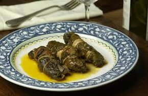 Le Mazzarelle al sugo sono uno dei piatti più rappresentativi della cucina contadina teramana, affondando le radici nella tradizione pasquale e agro-pastorale di questa terra. Si tratta di deliziosi involtini di scarola, dalla caratteristica forma rettangolare, che racchiudono al loro interno coratella di agnello, composta da polmone, fegato e cuore tagliati a listarelle e conditi con sapienza. In passato, le mazzarelle venivano preparate esclusivamente nel periodo primaverile, in occasione della Pasqua, diventando un simbolo della celebrazione in famiglia. Nonostante l’origine umile, legata al recupero delle parti meno nobili dell’agnello, queste preparazioni hanno saputo trasformarsi in una prelibatezza gastronomica di grande successo. Le mazzarelle nascono dall’ingegno delle massaie della comunità contadina, che desideravano creare un piatto gustoso pur utilizzando ingredienti semplici e accessibili. La coratella, considerata una parte di scarto e quindi più economica, diventava protagonista grazie alla sua preparazione accurata e alla combinazione con la scarola fresca. Il risultato era un piatto nutriente e saporito, espressione della cucina povera ma ricca di sapori autentici. Oggi, questo piatto non solo mantiene viva la tradizione, ma rappresenta anche un importante tassello del patrimonio gastronomico abruzzese, come dimostrato dal riconoscimento PAT (Prodotti Agroalimentari Tradizionali), che ne certifica l’autenticità e il valore culturale. Preparare le mazzarelle richiede tempo e dedizione, specialmente nella pulizia accurata delle budella di agnello, che svolgono il ruolo fondamentale di legare gli involtini. Le budella devono essere sciacquate più volte in acqua fredda e aceto, con l’aggiunta di sale, fino a raggiungere una pulizia perfetta e una colorazione chiara. Parallelamente, anche la coratella deve essere trattata con attenzione, tagliata a listarelle e ben condita per valorizzare il suo sapore. La scarola, con la sua freschezza e le sue note lievemente amare, avvolge il ripieno, donando al piatto un equilibrio unico di aromi e consistenze. Le mazzarelle si possono gustare sia in bianco che al sugo, ma è quest’ultima versione a regalare il caratteristico sapore rustico e intensamente aromatico della cucina teramana. Il sugo, preparato con pomodori freschi e un soffritto di aglio e cipolla, arricchisce il piatto e lo rende ancora più avvolgente. Quando adagiate sul piatto, con la loro forma rustica e il loro profumo inconfondibile, le mazzarelle raccontano la storia di una cucina che, con pochi e semplici ingredienti, è capace di creare un vero capolavoro gastronomico, celebrando le radici e le tradizioni culinarie della provincia di Teramo.