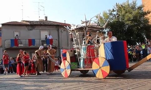 Il Palio delle Pupe è una delle tradizioni più vivaci e coinvolgenti della provincia di Pescara, che si celebra ogni anno a Ferragosto a Cappelle sul Tavo. Questa festa, che ha avuto inizio nel 1976, è un appuntamento che unisce arte, folklore e spirito di comunità. Le 14 contrade del paese si sfidano nella creazione della “pupa”, un fantoccio di cartapesta che rappresenta una figura femminile prosperosa. Il concorso non è solo un’esibizione di abilità artigianale, ma un’occasione per rivivere l’identità storica e culturale del territorio, dove ogni contrada porta avanti una tradizione che si tramanda da generazioni. Le pupe, realizzate con grande maestria, non sono semplici statue decorative, ma vere e proprie opere d’arte. All’interno di ciascuna pupa, che ha una struttura cava, si inserisce un ballerino professionista che, a ritmo di mazurka, polka e valzer, danza mentre la pupa si anima con giochi di luce e fuochi d'artificio. Questi fuochi, che esplodono dal castello costruito attorno alla pupa, aggiungono un tocco magico all’esibizione, creando uno spettacolo visivo che incanta i presenti. La combinazione di danza, colori e suoni rende il Palio delle Pupe un’esperienza emozionante, che coinvolge tutti i sensi e cattura l'immaginazione di chi vi partecipa. Il lavoro di preparazione per il Palio inizia mesi prima della festa, con le contrade che si dedicano alla creazione delle pupe e alla costruzione dei carri che sfileranno per le strade del paese. Le vie delle contrade vengono decorate con stendardi e bandiere colorate, che riflettono l’appartenenza a ciascun gruppo. Ogni dettaglio è pensato per esprimere la tradizione e lo spirito di collaborazione della comunità. Durante la sfilata del 15 agosto, i carri e le pupe, accompagnati da gruppi di sbandieratori e majorettes, percorrono le strade di Cappelle sul Tavo, rendendo il paese un palcoscenico di colori, suoni e allegria. L’atmosfera che si respira durante il Palio delle Pupe è unica. La festa non è solo un momento di intrattenimento, ma anche una celebrazione della cultura popolare abruzzese, che trova nel folklore e nelle tradizioni un mezzo per mantenere vivi i legami comunitari. I festeggiamenti coinvolgono tutti, dai più giovani ai più anziani, creando un forte senso di appartenenza e di identità collettiva. La partecipazione della comunità è il cuore pulsante dell'evento, che vede la collaborazione di tutti per realizzare un’occasione di festa che unisce arte, spiritualità e divertimento. Il Palio delle Pupe di Cappelle sul Tavo, dunque, non è solo una festa estiva, ma un vero e proprio atto di valorizzazione della tradizione popolare. Ogni anno, questa manifestazione richiamano non solo i residenti, ma anche numerosi turisti, che vengono a scoprire l’essenza di un paese che conserva e celebra le sue radici. La bellezza dei carri, la maestria delle pupe e la magia dei fuochi d’artificio rendono il Palio delle Pupe un evento che non solo racconta la storia di Cappelle sul Tavo, ma anche quella di un intero territorio, che attraverso il folklore perpetua i valori della tradizione e della comunità.