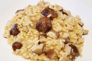 Il Risotto con i funghi porcini rappresenta uno dei piatti più amati della cucina tradizionale abruzzese, in particolare nella provincia di Teramo, dove la ricchezza della natura e la varietà di prodotti tipici si riflettono nella gastronomia locale. I funghi porcini, raccolti nei boschi del Gran Sasso e della Maiella, sono il cuore di questa ricetta. La loro carne bianca e compatta, insieme al loro intenso aroma di terra e di bosco, dona al risotto un sapore unico e avvolgente. La freschezza di questi funghi è essenziale per ottenere un piatto ricco e profumato. Per iniziare, i funghi porcini vengono accuratamente puliti e tagliati a fettine sottili. In un tegame, vengono poi saltati insieme a un soffritto di cipolla e olio extravergine d’oliva, un altro prodotto tipico abruzzese. L'olio d'oliva, di altissima qualità, conferisce al piatto una base leggera ma saporita, e la cipolla dolce, tritata finemente, arricchisce il tutto con il suo profumo delicato. Il vino bianco secco, come il Trebbiano d’Abruzzo, viene aggiunto per sfumare il soffritto, arricchendo ulteriormente il piatto con una nota fresca e acida che bilancia i sapori robusti dei funghi. Il risotto viene quindi cotto a fuoco lento, con l’aggiunta di brodo caldo preparato in precedenza, che deve essere versato poco alla volta per permettere al riso di assorbire i sapori. Il brodo, preparato con carne di manzo o pollo, è un altro elemento fondamentale della cucina teramana, che arricchisce ogni piatto con il suo gusto pieno e rotondo. Ogni chicco di riso si impregna progressivamente del brodo e dei funghi, sviluppando una consistenza cremosa che è il segno distintivo di un risotto ben fatto. Infine, per completare il piatto, il risotto viene mantecato con una generosa dose di parmigiano reggiano, prodotto che ben si sposa con la cucina abruzzese, e una spolverata di prezzemolo fresco tritato. Il parmigiano aggiunge cremosità e profondità al risotto, mentre il prezzemolo conferisce freschezza e colore. Il Risotto con i funghi porcini è così pronto per essere servito, un piatto che celebra i prodotti tipici di Teramo e della sua provincia, dove ogni ingrediente ha una storia e un legame profondo con il territorio.