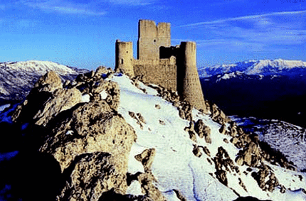 Rocca Calascio è uno dei luoghi più iconici d’Abruzzo, situata a 1.460 metri di altitudine nel cuore del Parco Nazionale del Gran Sasso e Monti della Laga. Questa suggestiva roccaforte, immersa in un paesaggio mozzafiato, domina la valle del Tirino e offre una vista che spazia fino alla Maiella e alla costa adriatica. Costruita nel Medioevo, probabilmente intorno al X secolo, la Rocca aveva una funzione strategica di avvistamento e difesa lungo l’antica Via degli Abruzzi, un’importante arteria commerciale e militare. L'architettura della Rocca colpisce per la sua semplicità e solidità. La torre principale, a pianta quadrata, è circondata da una cinta muraria intervallata da quattro torri cilindriche, aggiunte successivamente nel XV secolo. Questa struttura permetteva una difesa efficace contro gli attacchi nemici, sfruttando al massimo la posizione impervia del luogo. Nonostante i segni del tempo e i danni causati dal terremoto del 1703, la Rocca è oggi uno degli esempi meglio conservati di architettura militare medievale in Italia. 