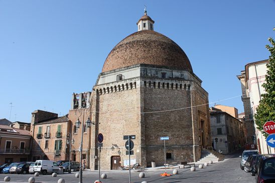 Il Duomo di San Flaviano di Giulianova, esempio di architettura rinascimentale, sorge a Giulianova ed è consacrato a San Flaviano, le cui spoglie raggiunsero fortunosamente le coste giuliesi poco prima del 450. Edificato negli anni settanta del XV secolo il Duomo è stilisticamente influenzato dall'architettura toscana e umbra del tempo. La tipologia militaresca ravvisabile nella straordinaria ampiezza delle mura (2 metri circa), nelle lesene di rinforzo agli angoli, nei beccatelli e nelle caditoie che ornano i lati, pone l'edificio per imponenza come il primo esempio nell'Abruzzo adriatico, dunque vero e proprio esperimento progettuale. Ha forma ottagonale, come solito nella simbologia di riferimento ai santuari mariani, ed era in principio isolato dal resto delle abitazioni (che dal XVI/XVII secolo vi si collegano nel lato meridionale), ancora a conferma del tentativo di rispettare i canoni di una costruzione ideale. A sormontarla una cupola, poggiante su un tamburo, dall'intradosso emisferico ed estradosso slanciato a congiungersi alla lanterna ottagonale. La calotta del Duomo di San Flaviano di Giulianova è rivestita di embrici semicircolari in cotto (un tempo in Maiolica azzurra con effetto rifrangente, che la rendeva un voluto punto di riferimento visibile dal mare a notevole distanza). L'interno, praticamente spoglio dopo i restauri del 1926 e del 1948 (questi ultimi ad opera di Arnaldo Foschini) volti al ripristino della spazialità quattrocentesca, erano stati decorati, in età tardorinascimentale e barocca con affreschi e ornamenti (come paraste e decorazioni a conchiglia). Altre opere ora non più presenti sono una croce processionale di Nicola Da Guardiagrele e il reliquario in argento con i resti del Santo di Costantinopoli, rimpiazzate nella seconda metà del Novecento da pregevoli dipinti e sculture di artisti contemporanei (fra cui spiccano i nomi del giuliese Venanzo Crocetti, di Renato Coccia e di Aligi Sassu). Posta al di sotto della collegiata del Duomo di San Flaviano di Giulianova, una cripta, dalla impegnativa copertura voltata ad ombrello, contiene i resti del patrono e di alcune personalità giuliesi. La Chiesa di San Flaviano - Il Duomo. La Chiesa di San Flaviano rappresenta il Duomo di Giulianova, ovvero la sua Chiesa più importante, ed è ubicata a Giulianova Paese in Piazza Buozzi, in quella cioè che fu la Piazza d’Armi ai tempi del Duca d’Atri e Conte di Conversano Giulio Antonio Acquaviva. E’ dedicata al Santo Patriarca di Costantinopoli, le cui spoglie approdarono nell’anno 1004 forse per un naufragio della nave che le stava trasportando da Costantinopoli a Ravenna, sulle rive di quella che si chiamava ancora Castrum Novum. In ossequio all’evento, il nome mutò in Castel San Flaviano ed in località Terravecchia fu costruita una Chiesa dedicata al Santo ove collocare la preziosa teca. La costruzione del Duomo di San Flaviano di Giulianova, forse su disegno dell’architetto toscano Francesco di Giorgio Martini, viene fatta risalire al 1472, cioè al tempo della fondazione di Giulia Nuova, anche se fu ultimata nei primi anni del 1500. Alla sua apertura al culto fu intitolata a Santa Maria in Platea o Santa Maria in Piazza e solo in un secondo momento, dopo che nel 1478 vi erano state traslate le reliquie di San Flaviano dall’antica chiesa fuori delle mura cittadine, fu intitolata a San Flaviano. Il Duomo di San Flaviano di Giulianova è un monumento rinascimentale la cui pianta ottagonale ne fa un esempio quasi unico in Abruzzo, insieme alla imponente insolita cupola a calotta semisferica, che cronologicamente precede anche quella di S. Pietro, iniziata nel 1506. Al suo culmine una piccola lanterna, anch’essa ottagonale, sovrastata da una grande croce in ferro. Per la sua svettante altezza fu importante punto di riferimento per il territorio circostante e persino per i pescatori, tanto che si pensa che il rivestimento originario fosse costituito da mattonelle smaltate di azzurro con effetto volutamente rifrangente, assolutamente visibile anche da molto lontano. Al di sotto della grande aula della Chiesa si trova la cripta, il cui soffitto è un capolavoro di ingegneria, originariamente utilizzata per il culto e poi per molto tempo per la custodia delle reliquie del Santo. L’ingresso della cripta del Duomo di San Flaviano si trova subito sotto all’antico ingresso della Chiesa la cui tamponatura, forse avvenuta alla fine del 1800, è ancora visibile. In epoca tardo-rinascimentale l’interno della Chiesa di San Flaviano fu arricchito con affreschi ed ornamenti dell’epoca; in tempi recenti è stata più volte oggetto di restauro, nel 1871, nel 1895, nel 1926, nel 1939 (relativamente solo alla torre campanaria) e nel 1948, al fine di risolvere dei problemi connessi alla staticità e ad alcune gravi infiltrazioni d’acqua dal tetto. In queste occasioni furono eliminate via via tutte le decorazioni barocche nell’intento di far riguadagnare alla struttura tutta la semplicità cinquecentesca. La Chiesa di San Flaviano oggi è ricca di opere di contemporanei illustri: sull’altare di sinistra si trova la pregevole scultura in marmo “Madonna con Bambino” di Venanzo Crocetti (1913-2003); dello stesso scultore sull’altare maggiore del Duomo di San Flaviano di Giulianova si trova un bellissimo grande Crocefisso in bronzo realizzato nel 1959; a destra dell’altare maggiore lo scultore di Palestrina (Roma) Francesco Coccia (1902-1982) ha realizzato il Battistero in travertino istoriato con “Il Battesimo di Gesù” in bronzo; dello stesso autore troviamo l’Altare maggiore in pietra di Trani sormontato da un gruppo in bronzo raffigurante il Crocefisso, la Vergine e San Flaviano, del 1951; infine, le raffigurazioni della Via Crucis sono lavori a carboncino di Aligi Sassu (1912-2000). Su una delle pareti esterne che danno verso Corso Garibaldi nel 1922 è stata apposta una lapide in memoria dei concittadini caduti nella Prima Guerra Mondiale, i cui nomi sono scolpiti insieme al comunicato della vittoria diffuso dal Comando Supremo delle Forze Armate. Una grande aquila bronzea realizzata dallo scultore Ulderico Ulizio (1898-1987), allievo di Raffaello Pagliaccetti (1839-1900) sovrasta questo angolo della memoria. Il Duomo di San Flaviano. L’imponente Duomo di San Flaviano, realizzato a partire dal 1472 e originariamente chiamato S. Maria in piazza.