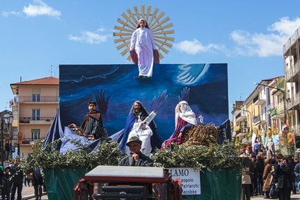 La Festa dei Talami di Orsogna è un evento che unisce la tradizione religiosa e il folklore in una celebrazione che si svolge ogni anno il Martedì dell'Angelo, poco dopo la Pasqua. La Festa dei Talami di Orsogna è una delle tradizioni più affascinanti e sentite della provincia dell'Aquila, celebrata ogni anno nel Martedì dell'Angelo, che segna la ripresa della vita dopo la Pasqua. Il paese, che si trova sulle colline abruzzesi, a breve distanza dal Parco Nazionale della Majella, diventa il palcoscenico di uno spettacolo che unisce fede, arte e folklore. Le strade del centro storico si riempiono di un’atmosfera speciale, in cui la comunità si raccoglie per celebrare la Madonna del Rifugio, protettrice del paese, con una processione che richiama fedeli e visitatori da ogni parte. La processione dei talami prende il nome dai carri allegorici, che sono veri e propri palchi su cui vengono rappresentate scene sacre ispirate alla Bibbia. Ogni quartiere di Orsogna è incaricato di allestire il proprio talamo, che diventa il cuore della sfilata. Gli attori, giovani e adulti del paese, interpretano scene del Vecchio e Nuovo Testamento davanti a un affresco della Madonna, rappresentata come una figura protettrice. I talami, portati inizialmente a mano dai membri della comunità, vengono ora trasportati su carri trainati da trattori, tranne l’ultimo, che per tradizione è trasportato a spalla dagli alpini. La festa ha radici molto antiche, che risalgono al 1270, quando, secondo la tradizione, la Vergine Maria apparve nel luogo dove sarebbe poi stata costruita la Chiesa della Madonna del Rifugio. La chiesa, che fu rasa al suolo dai bombardamenti nel 1944, rappresenta un simbolo di speranza e fede per gli abitanti di Orsogna. Il culto della Madonna Nera, affrescata sull'altare maggiore della chiesa, è il nucleo attorno a cui si sviluppa questa manifestazione popolare. Secondo la leggenda, la Madonna dispensava grazie miracolose, e nel giorno della sua festa, avveniva un fenomeno straordinario: gli occhi della Madonna si muovevano o il suo volto cambiava colore, un segno che i devoti interpretavano come un miracolo. Il giorno della festa, i talami vengono trasportati lungo le strade del paese fino a giungere nella piazza principale, dove la processione si conclude con una riflessione pubblica. Ogni talamo viene esaminato dal Vescovo che ne commenta il significato, dando alla festa una dimensione spirituale e collettiva. Le rappresentazioni bibliche, che vengono eseguite con grande devozione, raccontano le storie sacre in modo vivente, coinvolgendo il pubblico in un’esperienza che va oltre la mera osservazione, ma che diventa un atto di partecipazione emotiva e religiosa. La Festa dei Talami non è solo un evento religioso, ma una vera e propria celebrazione dell’identità culturale e sociale di Orsogna. La comunità si riunisce per mantenere viva una tradizione che affonda le sue radici in secoli di storia e che, nonostante le difficoltà, ha continuato a prosperare e a rinnovarsi. Ogni anno, la festa rappresenta un’occasione per riscoprire il legame con il passato, per tramandare la devozione religiosa e per rafforzare il senso di appartenenza a una comunità che, attraverso il folklore, celebra la sua fede e la sua storia.