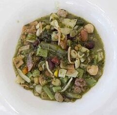 La preparazione delle "virtù" teramane inizia con la selezione degli ingredienti tipici della tradizione agricola abruzzese. I legumi secchi, come fagioli, ceci e lenticchie, sono il cuore del piatto, raccolti durante l’autunno e conservati con cura per l’inverno. Questi legumi vengono messi a cuocere separatamente, insieme alle verdure fresche che la primavera offre, come fave, cipolle, carote e spinaci. Ogni ingrediente deve essere preparato con attenzione per preservare il suo sapore naturale e la sua consistenza, in modo che, durante la lunga cottura, riesca a rilasciare il massimo del suo gusto. Il maiale è un altro protagonista indiscusso della ricetta. La cotica di maiale, simbolo della tradizione contadina, viene cucinata per aggiungere sapore e sostanza al piatto. La carne di maiale, che può includere anche pancetta o costine, viene unita ai legumi e alle verdure, dando al brodo un sapore ricco e corposo. La cotica, che rilascia un delicato grasso durante la cottura, contribuisce a rendere il piatto ancora più succulento e profumato. Questo mix di carne e verdure conferisce alla "virtù" un equilibrio perfetto di gusto e consistenza, che è il segreto del suo successo. La pasta, un altro elemento fondamentale, può essere sia fresca che secca. La pasta fresca, preparata con farina di grano duro e uova fresche, è un prodotto tipico dell’Abruzzo e aggiunge al piatto una consistenza morbida e avvolgente. La pasta secca, tradizionalmente usata in molte ricette abruzzesi, offre una texture più resistente e si sposa perfettamente con il brodo ricco e denso delle virtù. La pasta viene cotta nel brodo stesso, assorbendo tutti i sapori degli altri ingredienti, mentre la sua presenza rende il piatto completo e sostanzioso. Infine, la lunga cottura è essenziale per unire tutti questi ingredienti, che devono essere amalgamati lentamente per creare un piatto armonioso. Ogni fase della preparazione richiede pazienza e attenzione, poiché ogni ingrediente deve essere aggiunto al momento giusto e alla temperatura corretta per evitare che il piatto prenda un sapore troppo forte o si rovini. Una volta pronta, la "virtù" è servita come piatto unico, che non necessita di accompagnamenti, perché già ricca e soddisfacente di per sé. Con ogni cucchiaiata, si assapora la tradizione abruzzese, fatta di ingredienti semplici e genuini, che raccontano la storia di un popolo legato alla terra e al suo lavoro.
